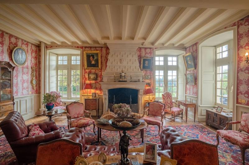Salon Rose : murs tendus de toile rose, portraits, cheminée et fauteuils autour d'une table basse