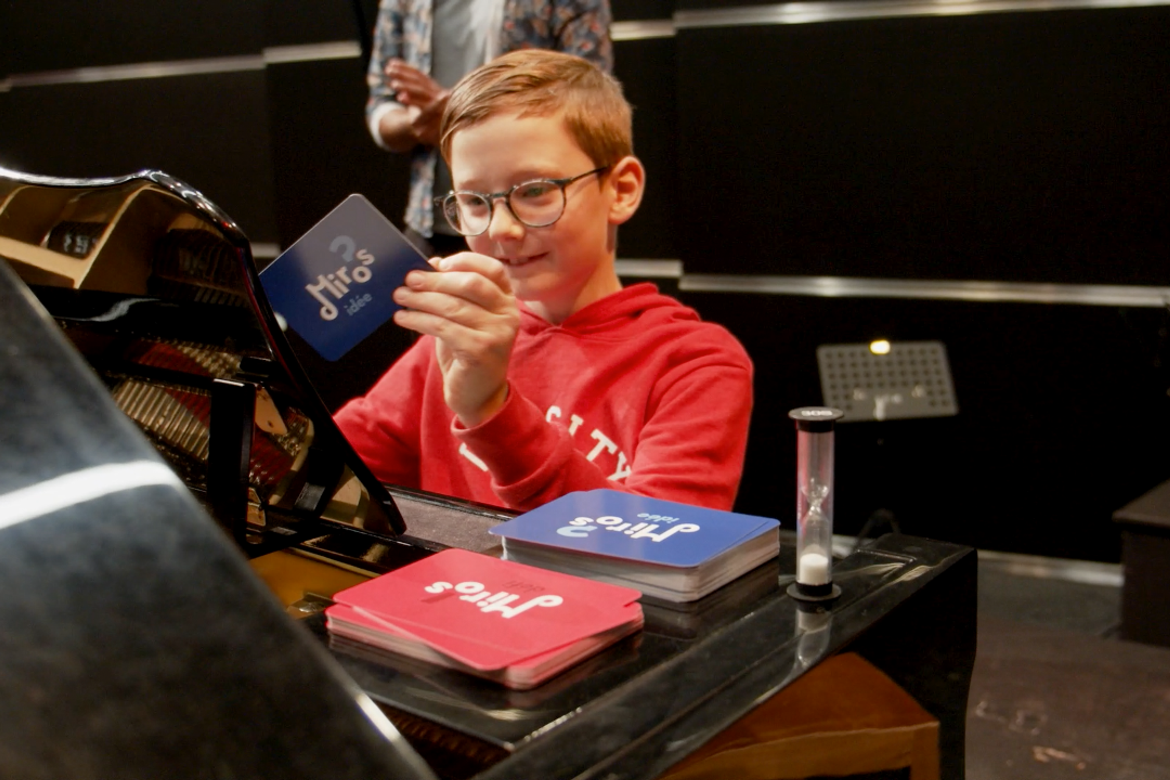 A young musician handling cards sitting at a piano