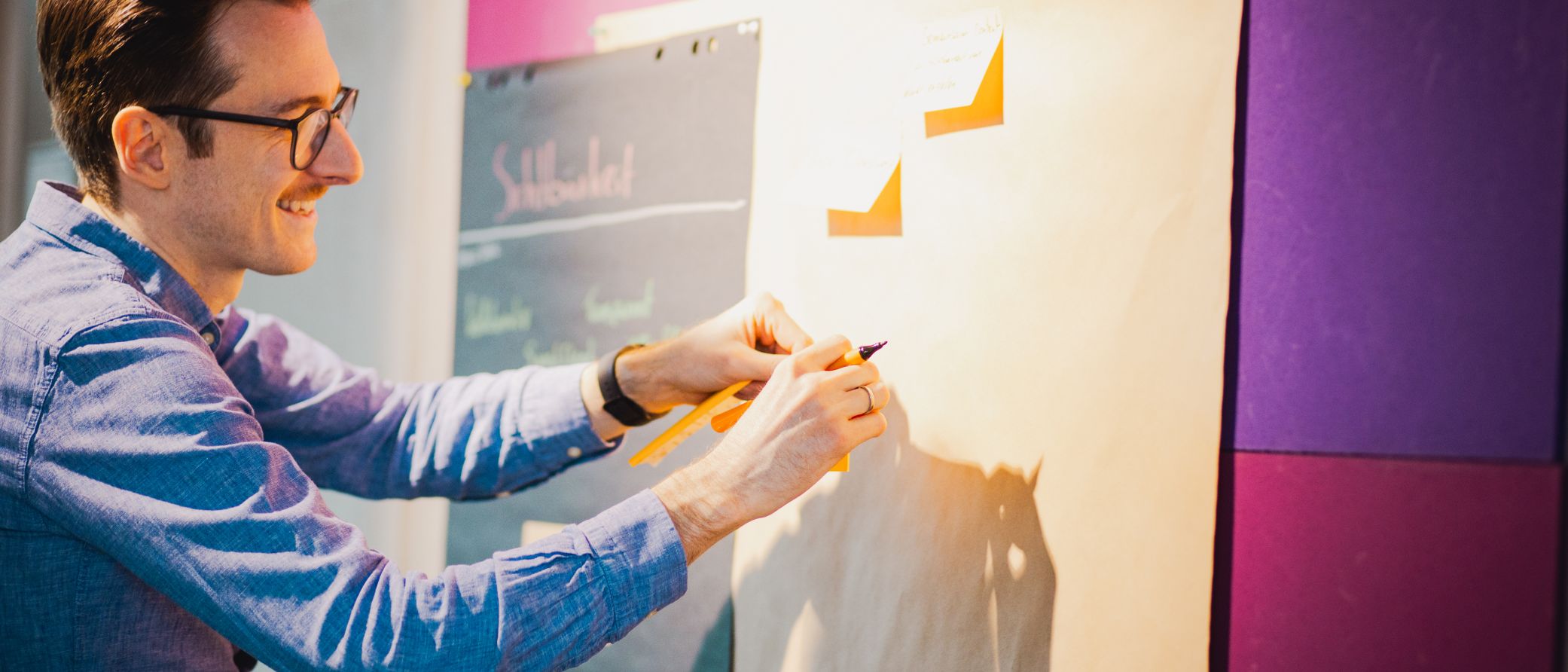 Discovery Workshop zur Nutzerforschung und digitalen Bedarfsanalyse bei mindmatters in Hamburg UX-Research-Workshop bei mindmatters: Kollege beschriftet Haftnotizen an einer Metaplanwand zur digitalen Bedarfsanalyse