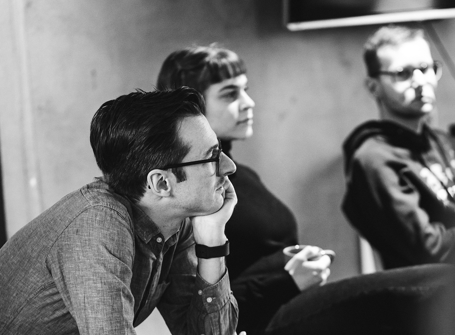 Drei Kolleg:innen aus der Softwareentwicklung vertieft in einer Teambesprechung