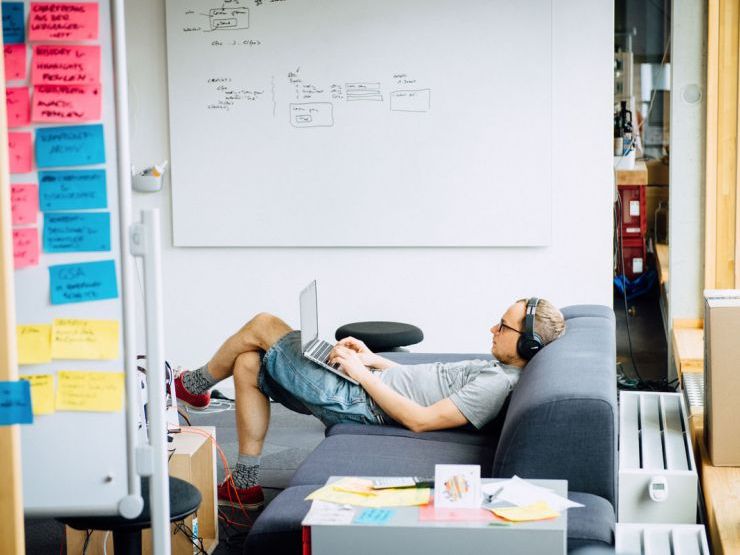 Bild eines Mitarbeiters mit Kopfhörern auf der Couch