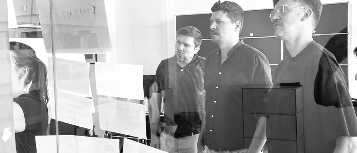 Agile Zusammenarbeit mit Softwareunternehmen – digitale Produkte gemeinsam gestalten Team bei der agilen Zusammenarbeit in einem Softwareprojekt am Whiteboard mit Stickies