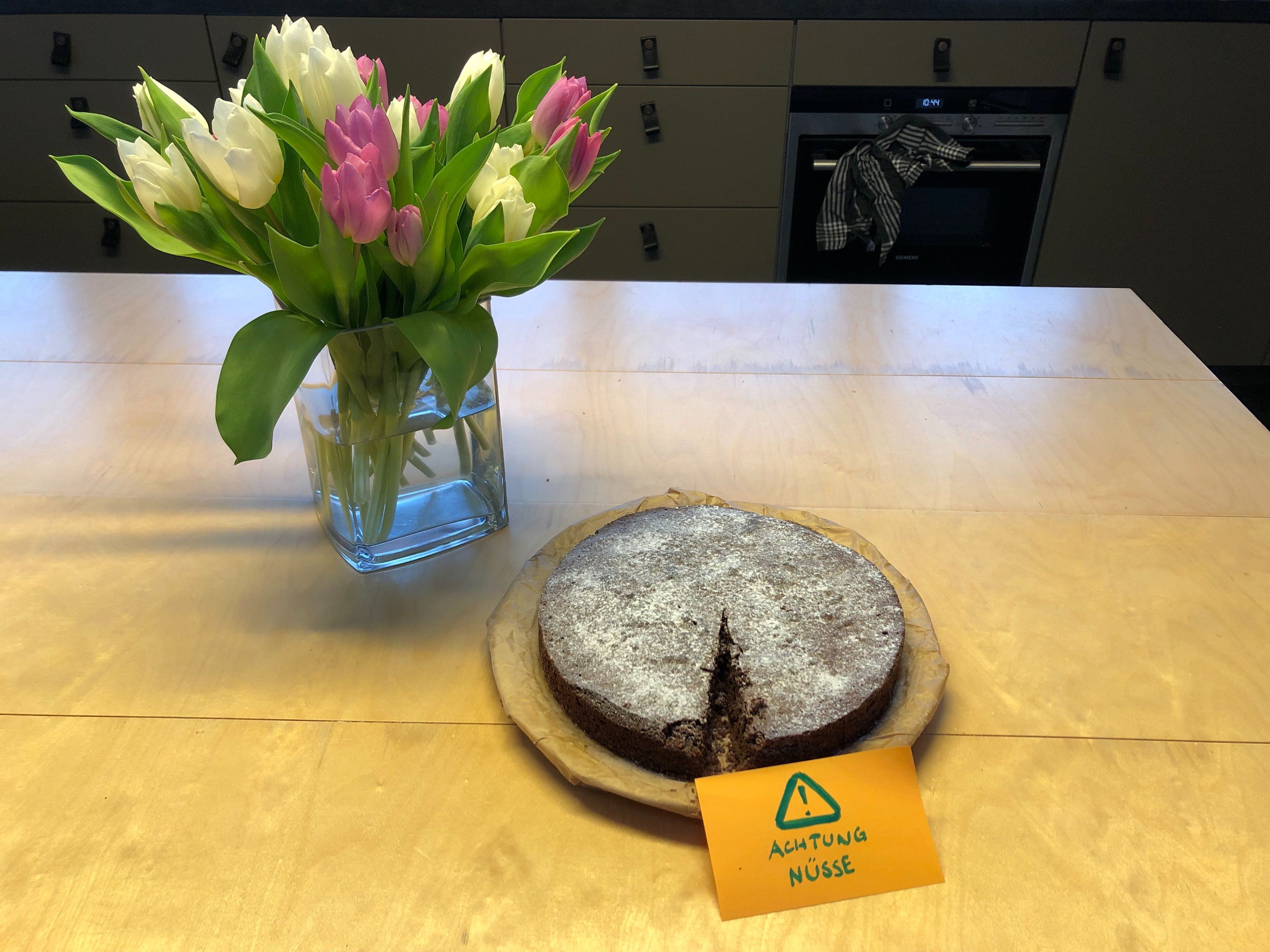 Bild eines Kuchens und Blumen auf dem Esstisch