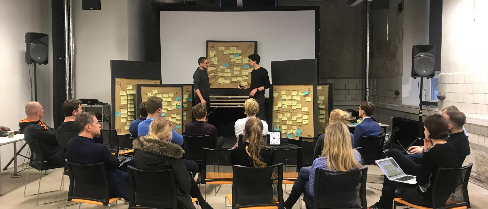 BIld eines Workshops mit Teilnehmern im Stuhl-Halbkreis versammelt