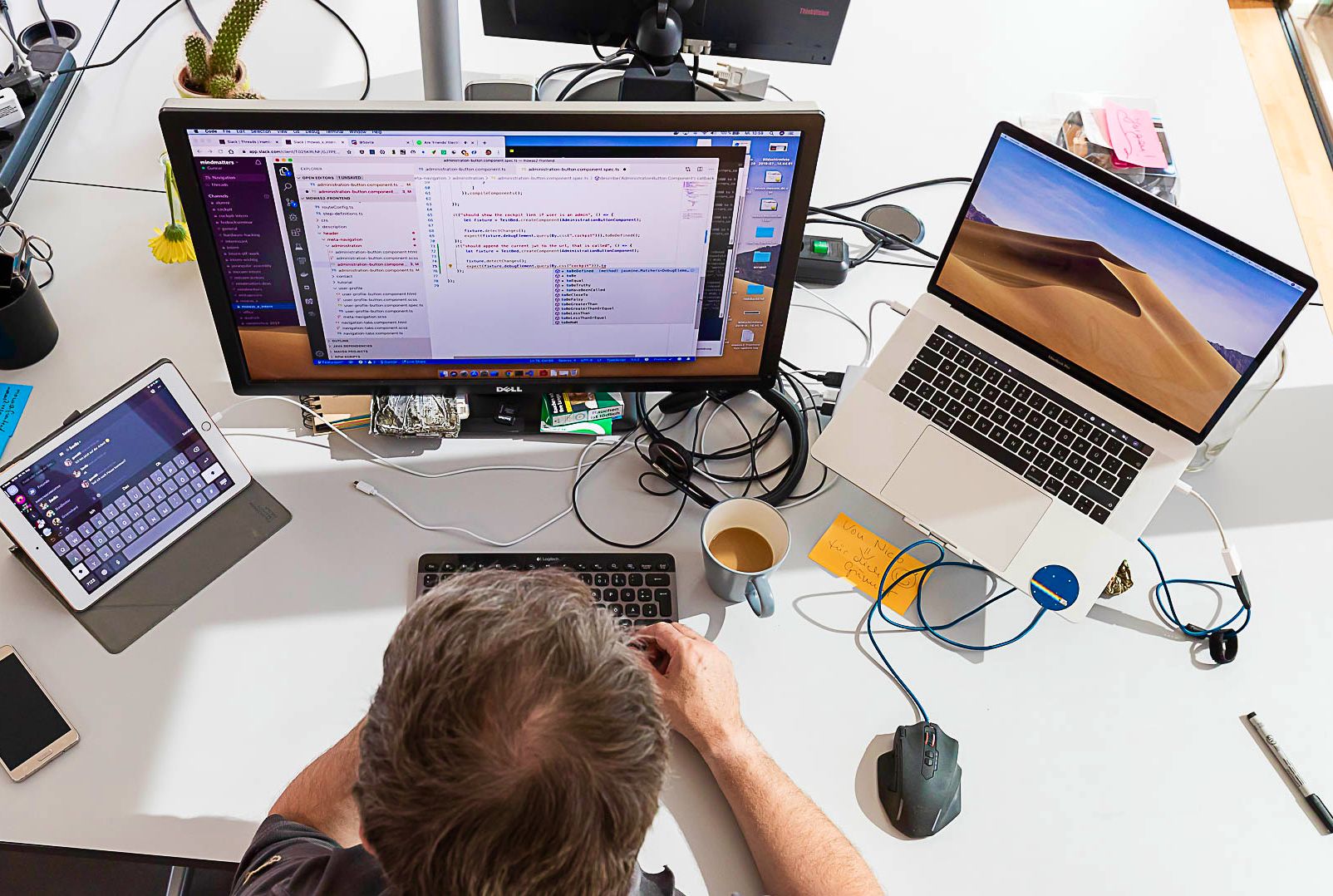 Softwareentwickler bei der Arbeit an individueller Softwarelösung mit drei Monitoren