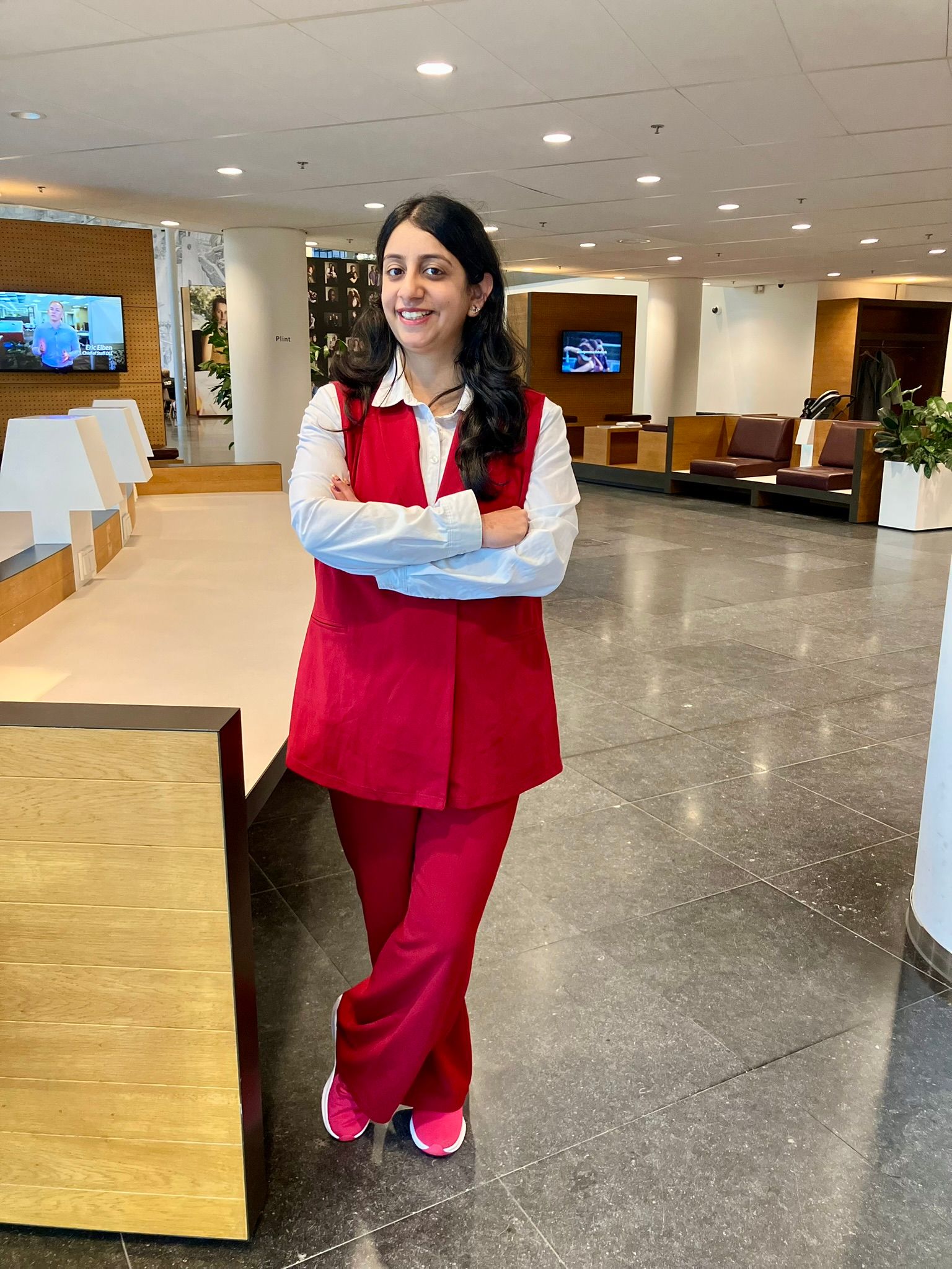 Woman wearing a red gilet with matching pants and sneakers at the office.