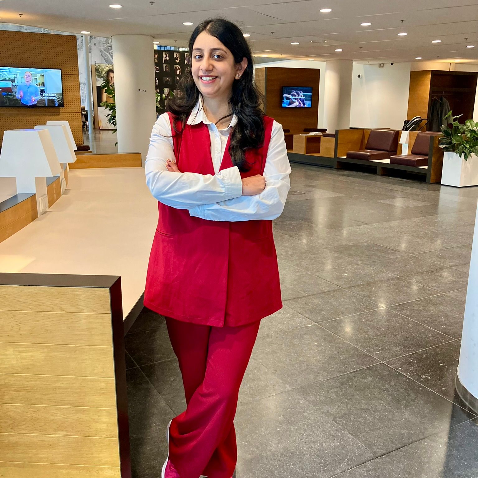 Woman wearing a red gilet with matching pants and sneakers at the office.