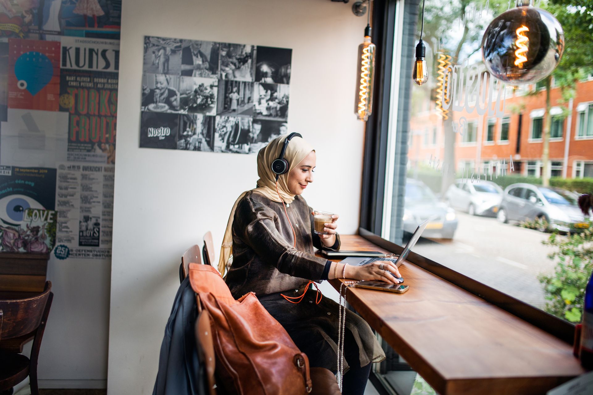 Enaam werkt op laptop in café.