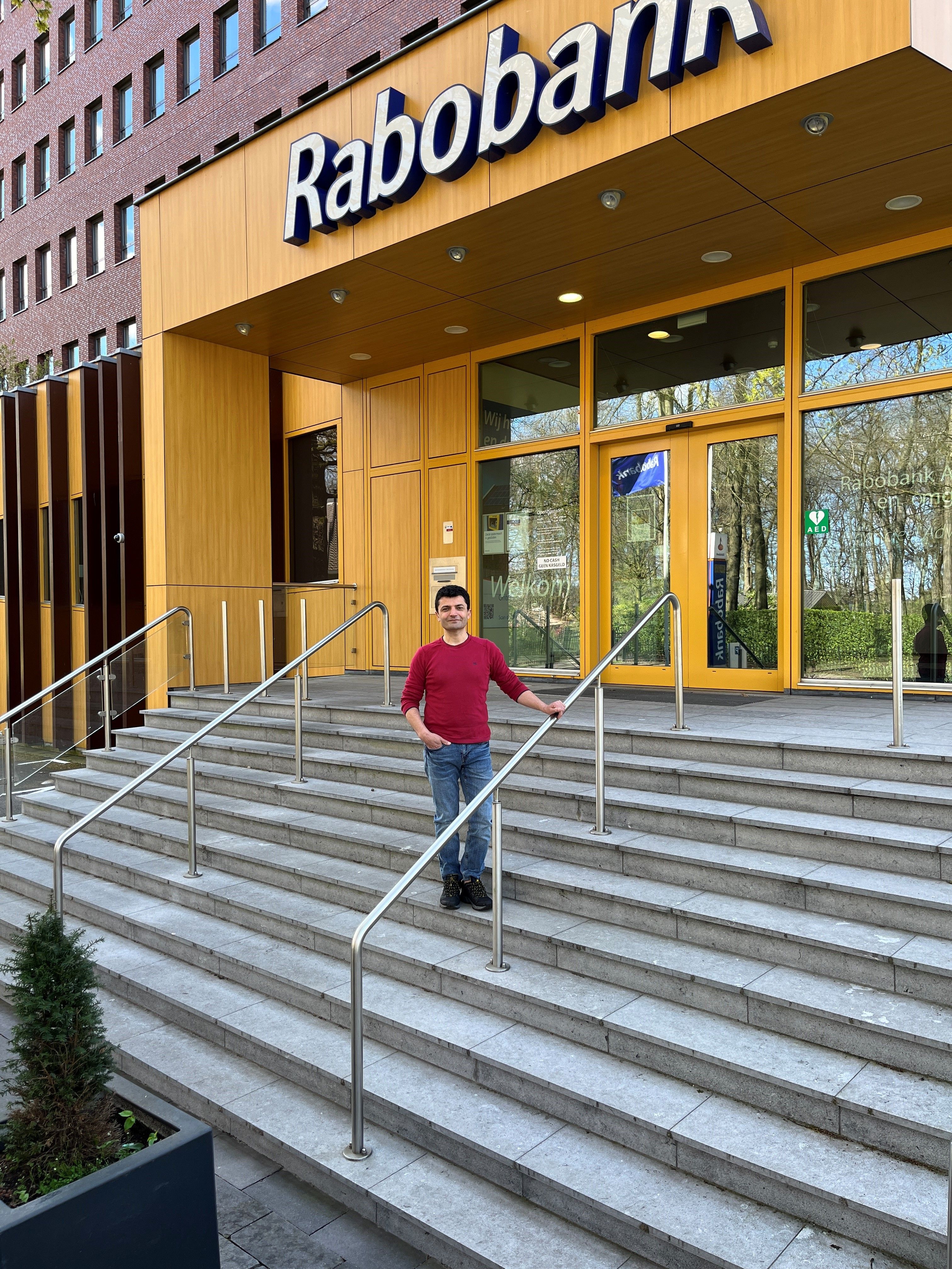 Man poseert op de trap voor een Rabobankkantoor