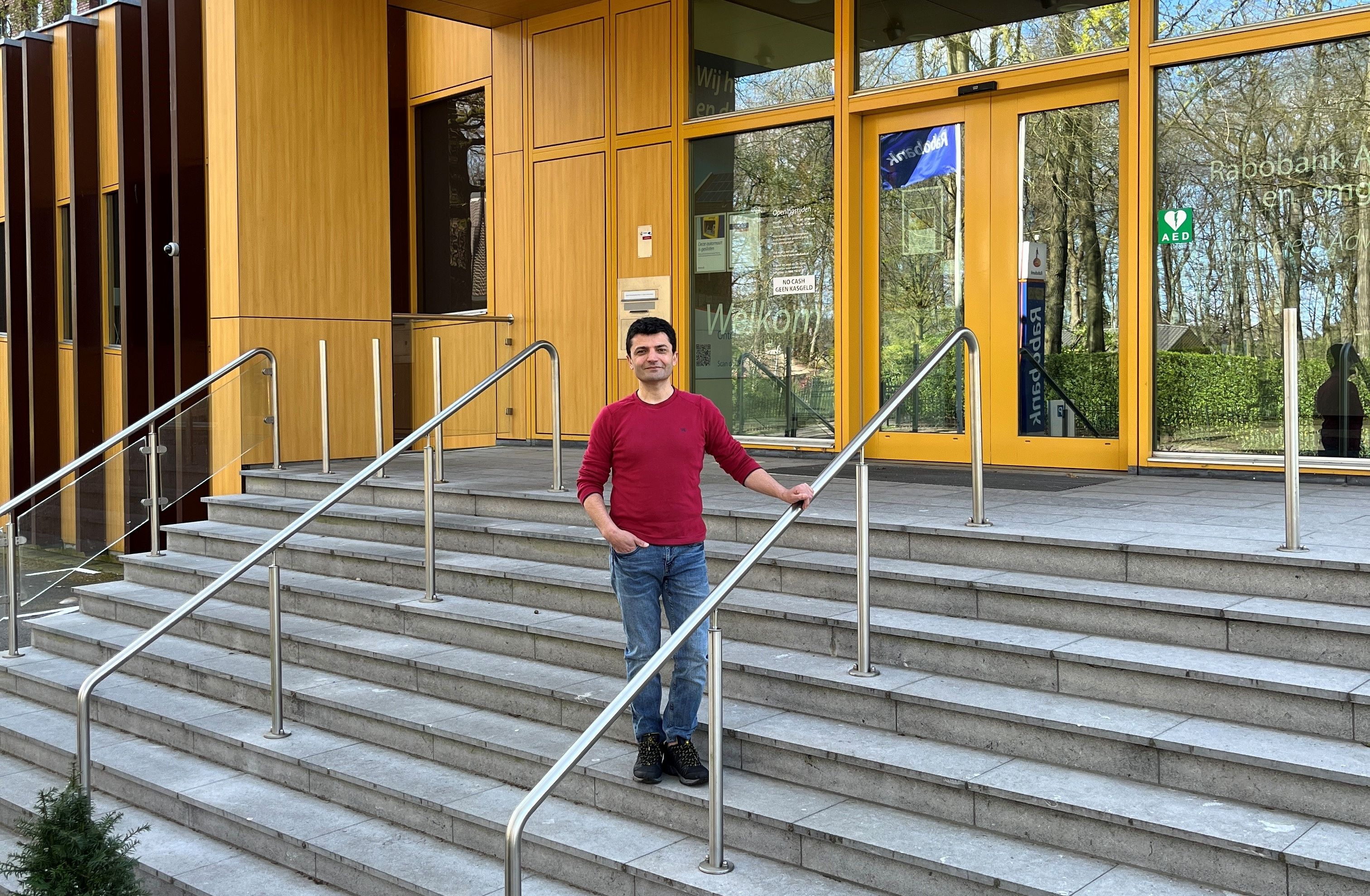 Man poseert op de trap voor een Rabobankkantoor