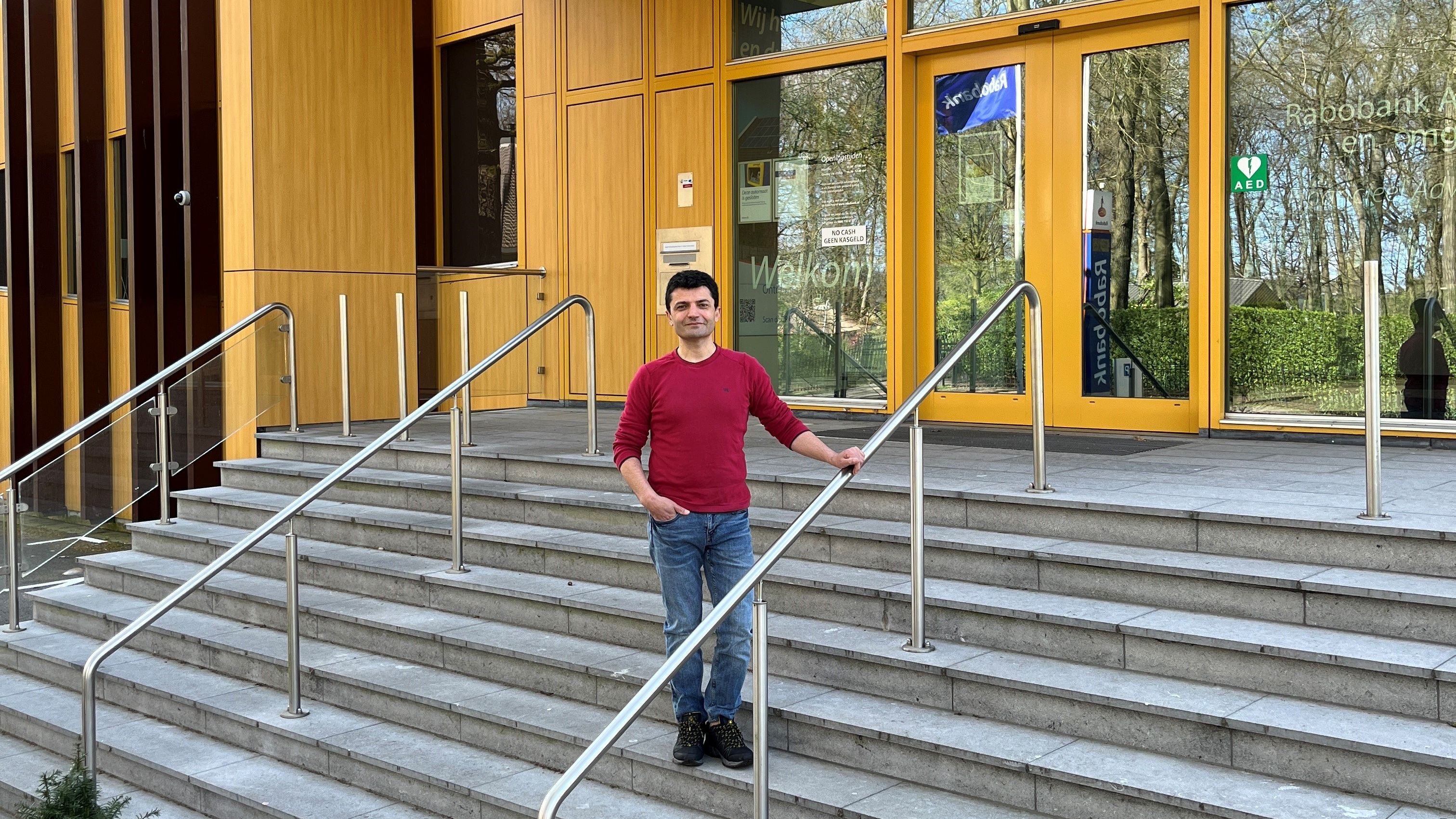 Man poseert op de trap voor een Rabobankkantoor
