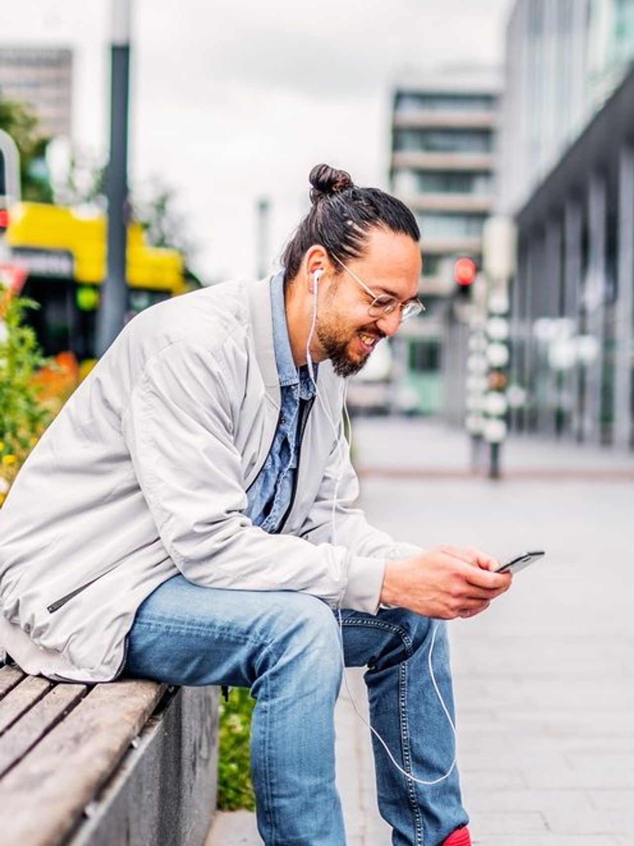 Man sits on bench and looks at cell phone.