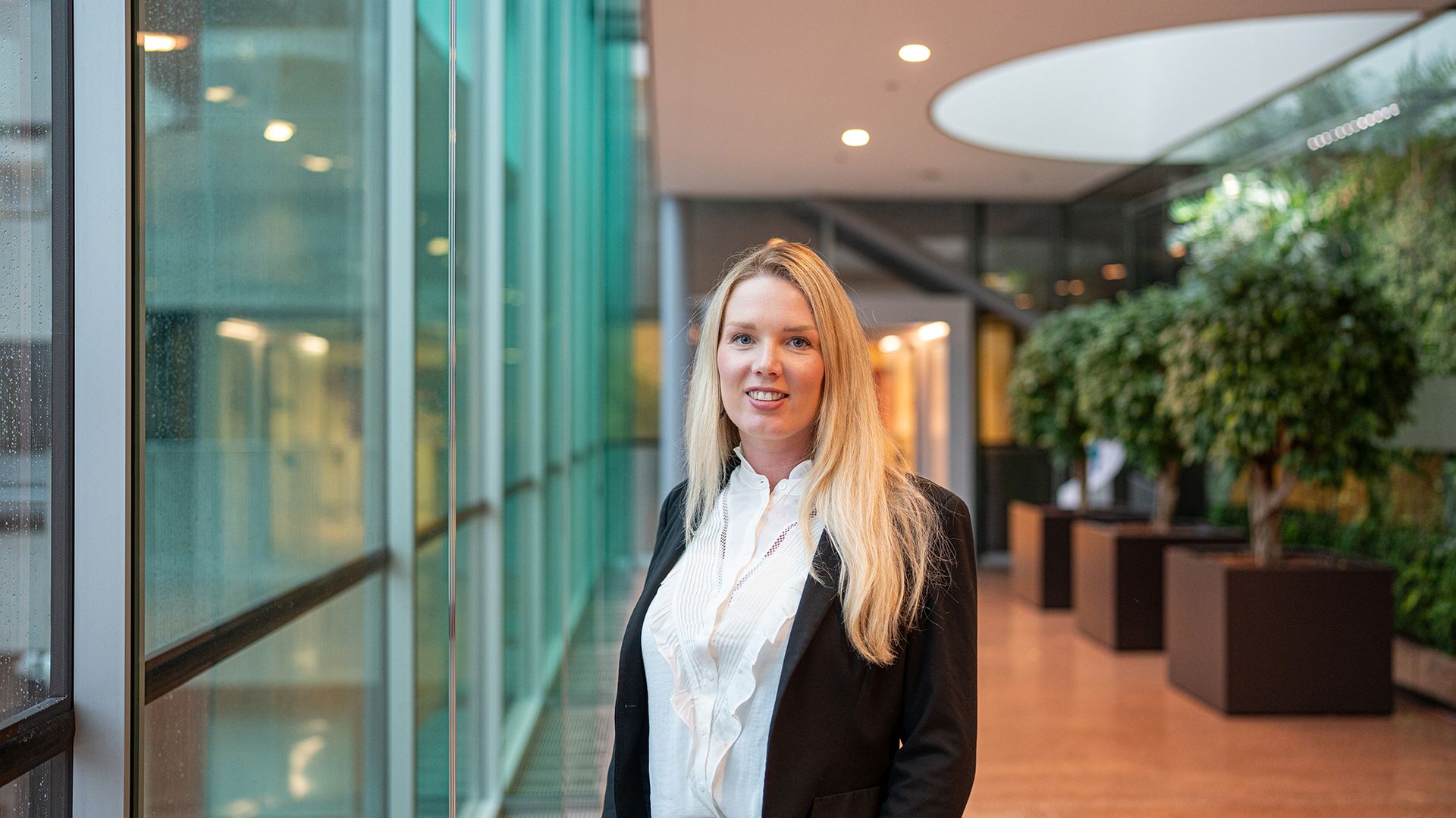 Stephanie Vrolijk (Transaction Banker) naast glazen wand.