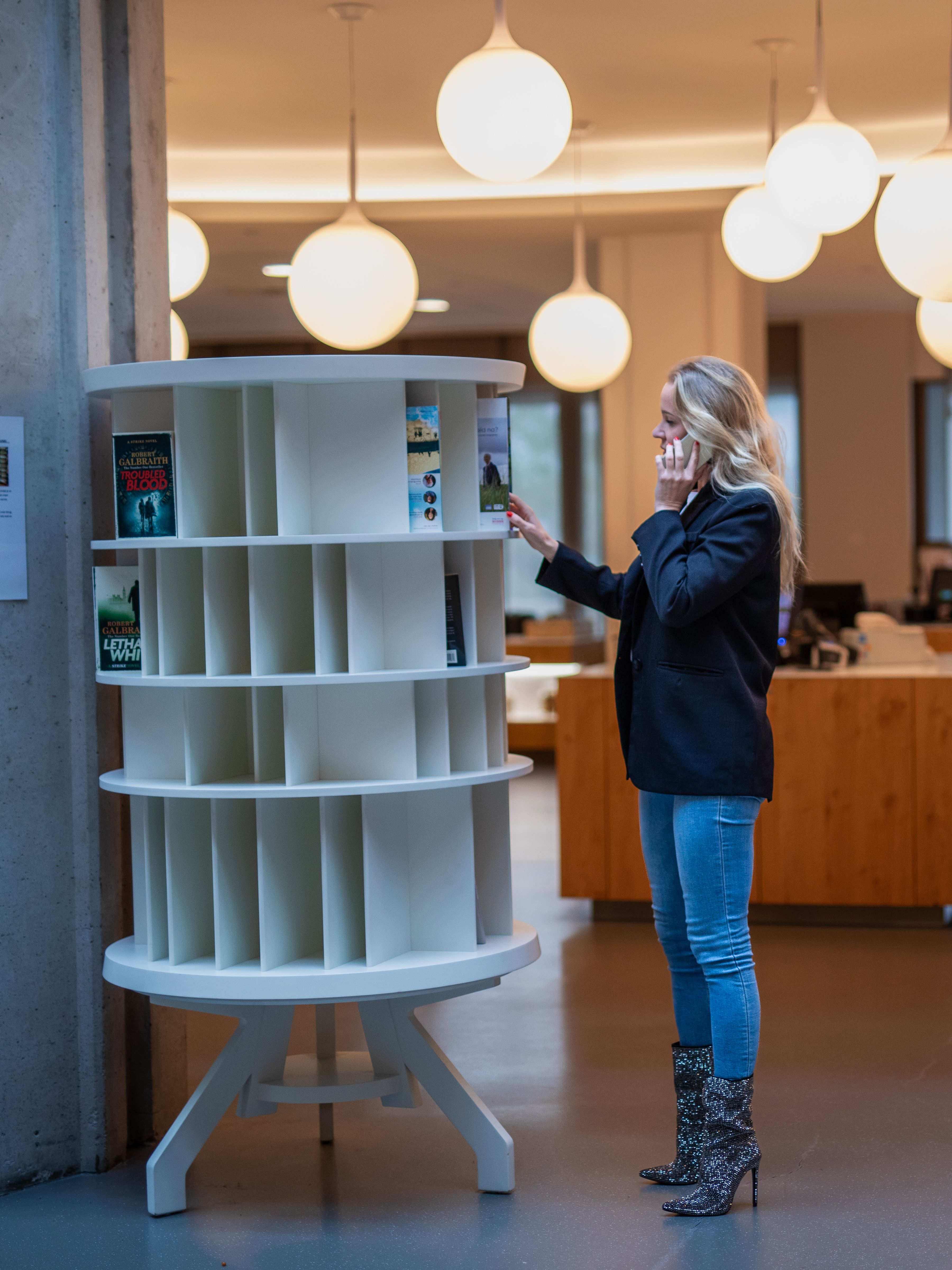 Vrouw belt terwijl ze door boekenkast bladert