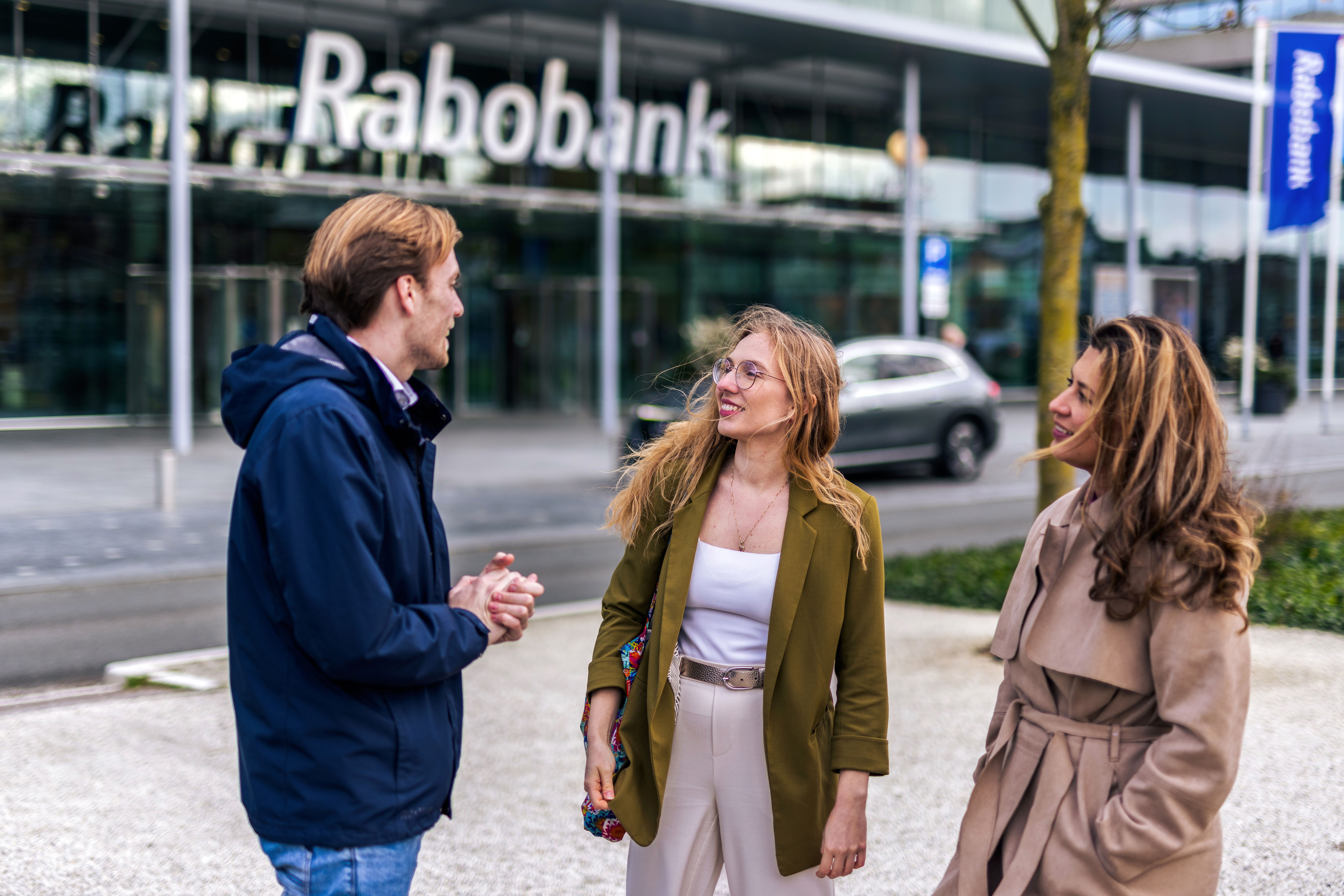 Three colleagues are standing in front of Rabobank office