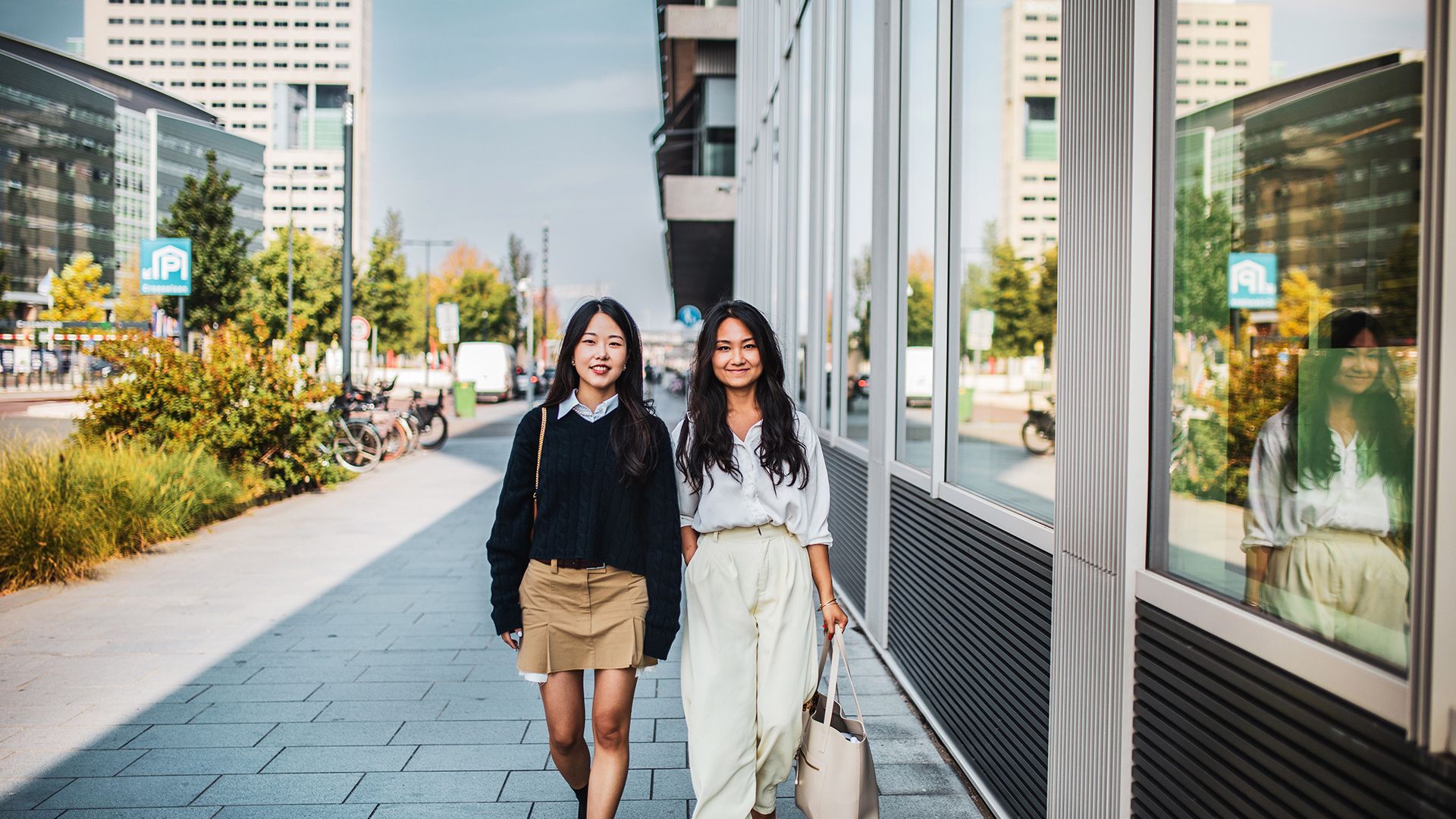 Young women walking next to office building.