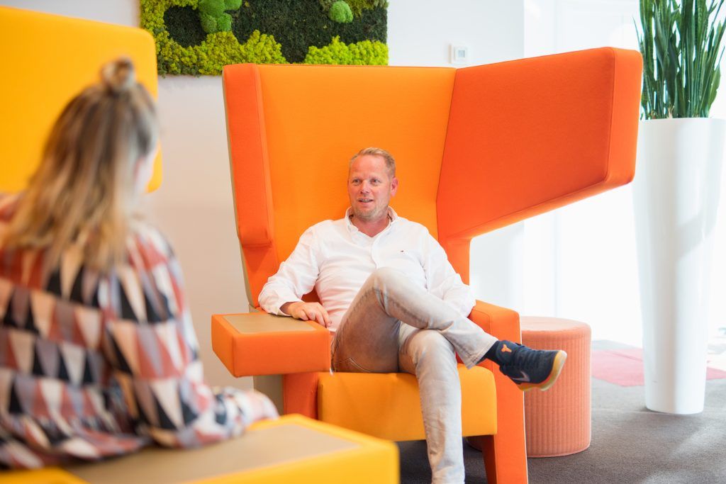 Man zit in oranje stoel.