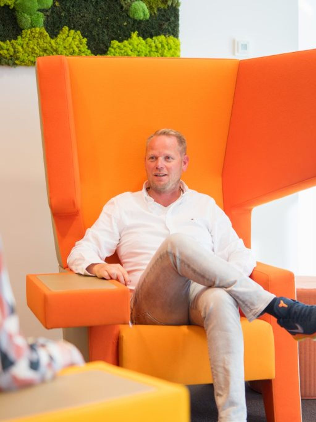 Man zit in oranje stoel.