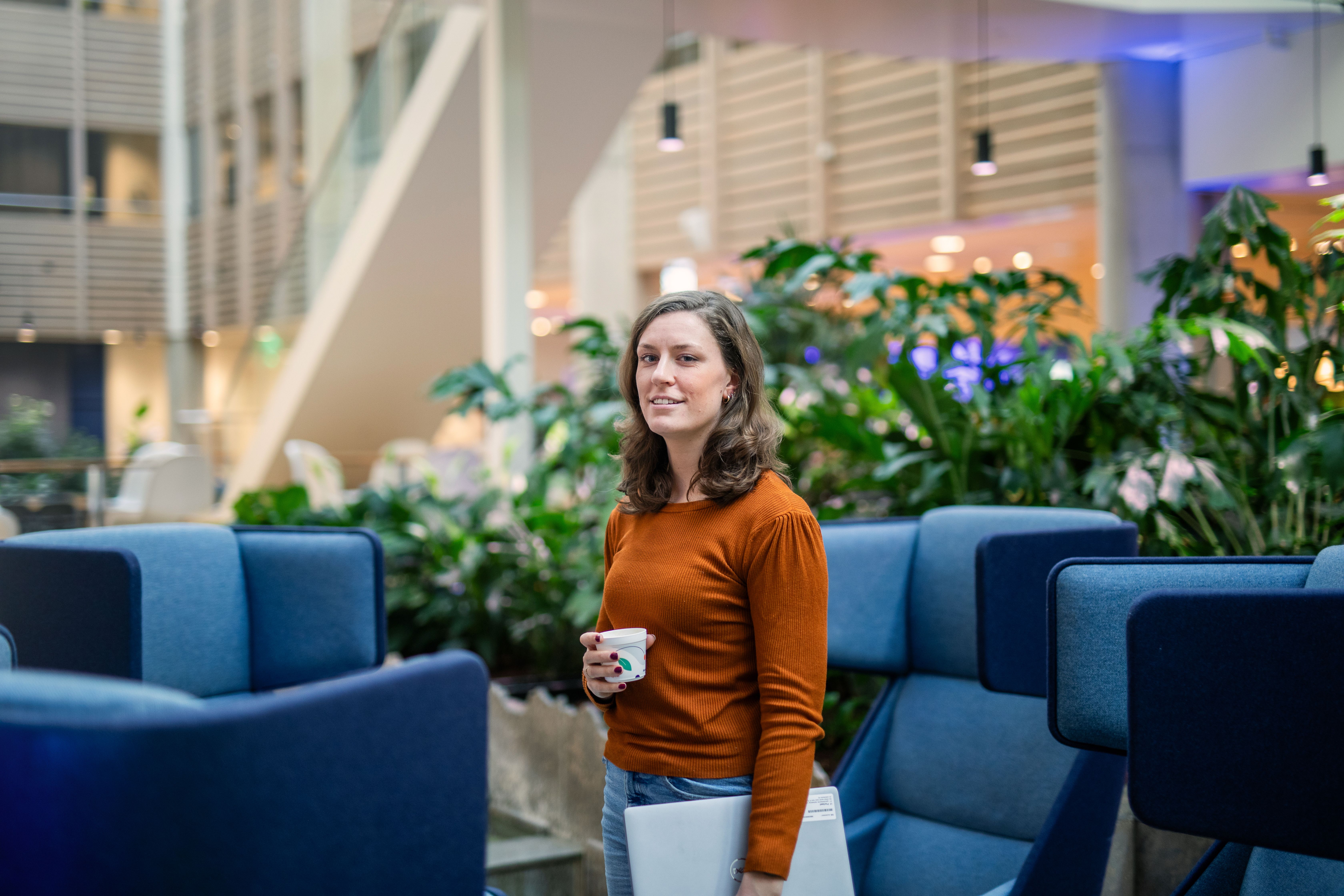 Vrouw op kantoor met laptop onder arm