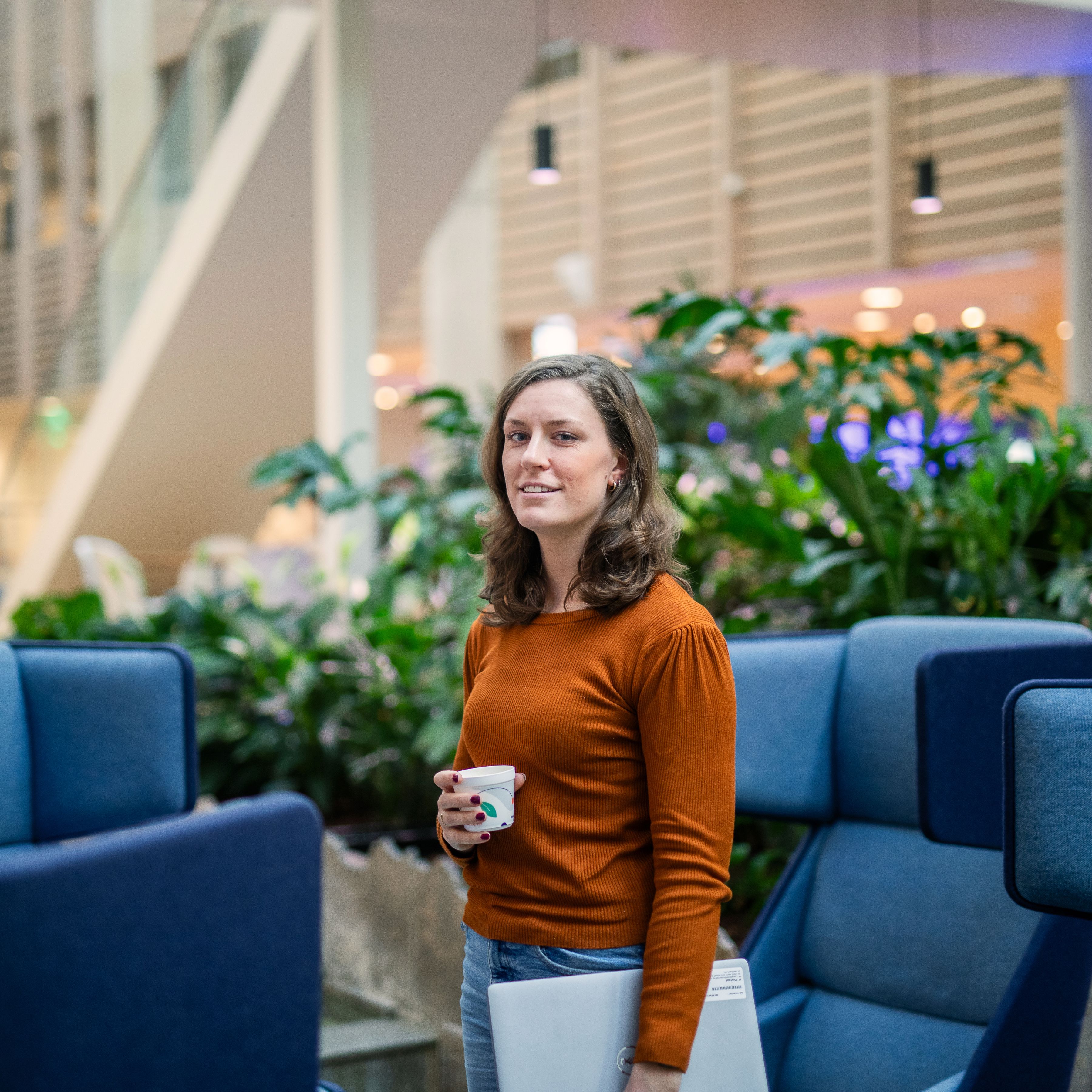 Vrouw op kantoor met laptop onder arm