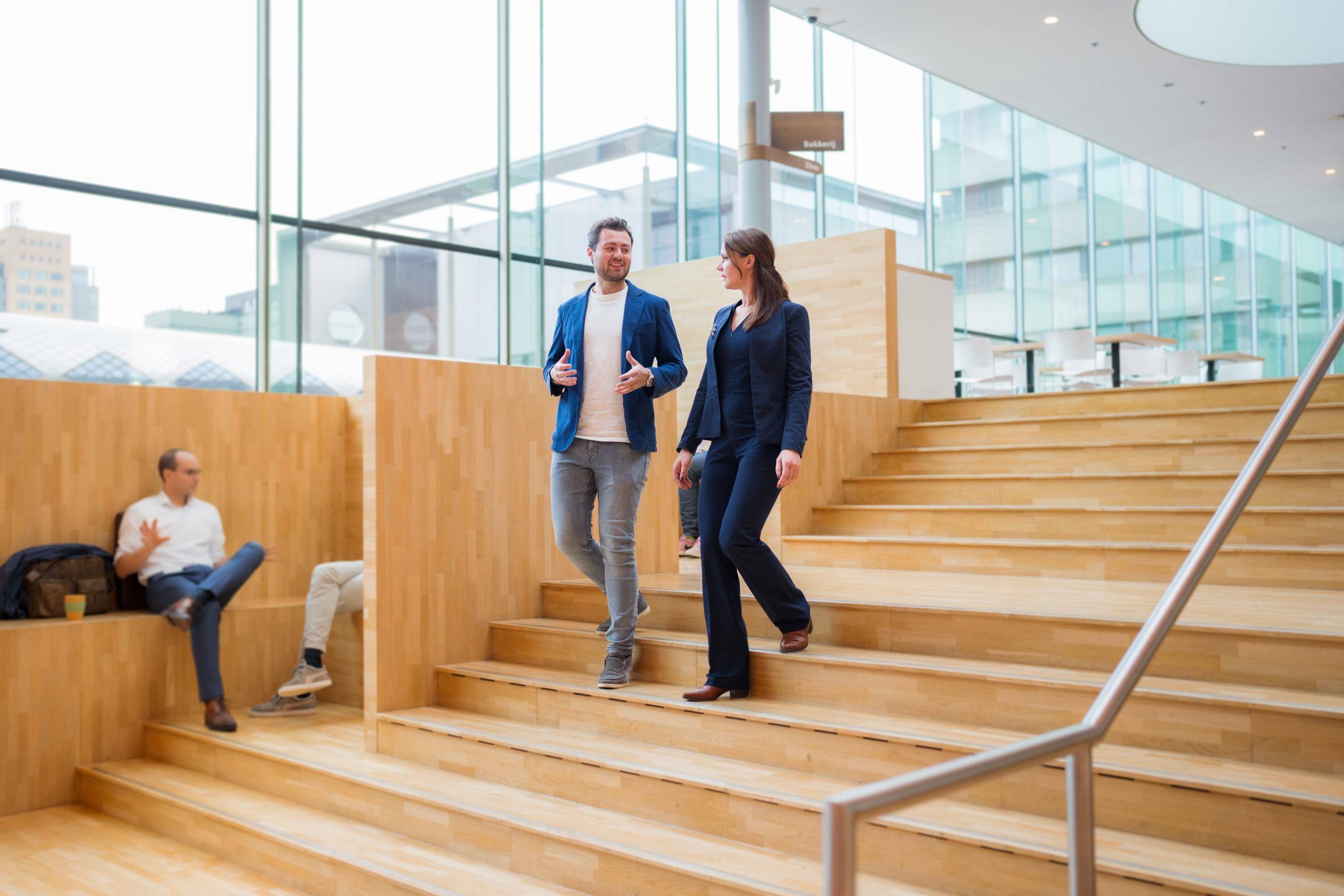 Man en vrouw in gesprek lopend op trap.