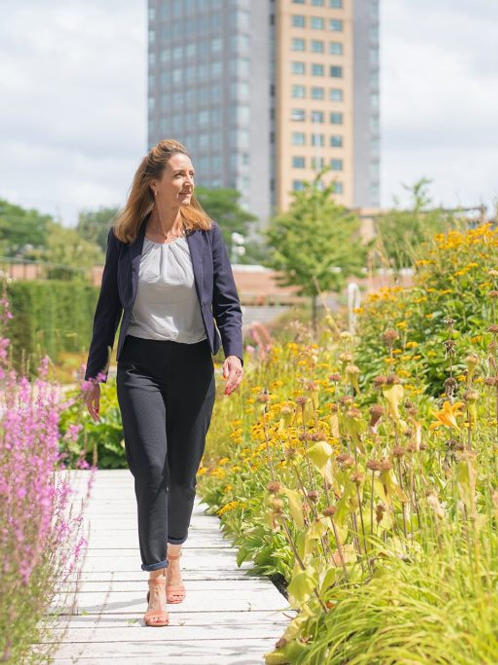Woman in suit walks through flowering garden
