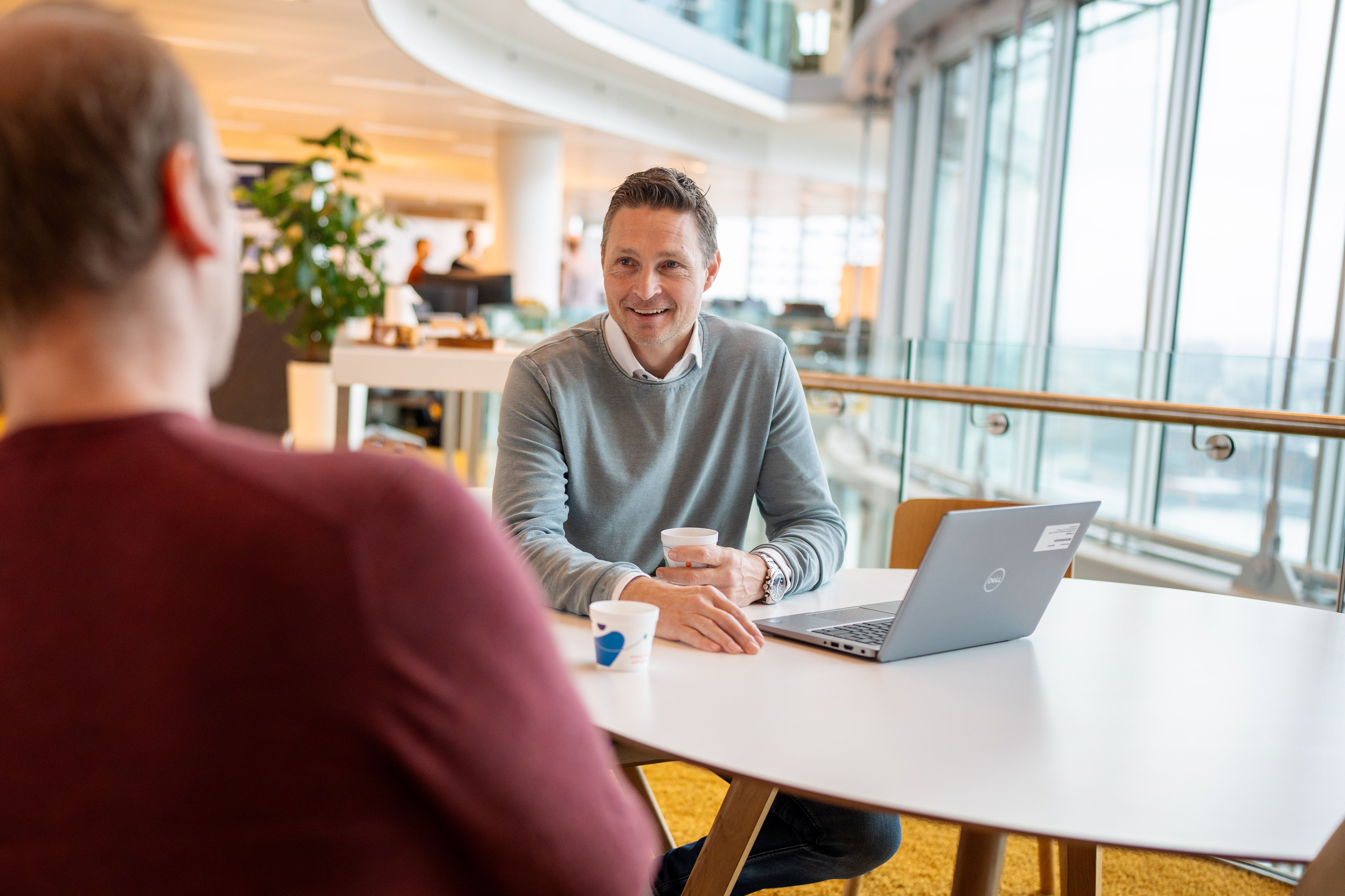 man talking with a collague next to a laptop
