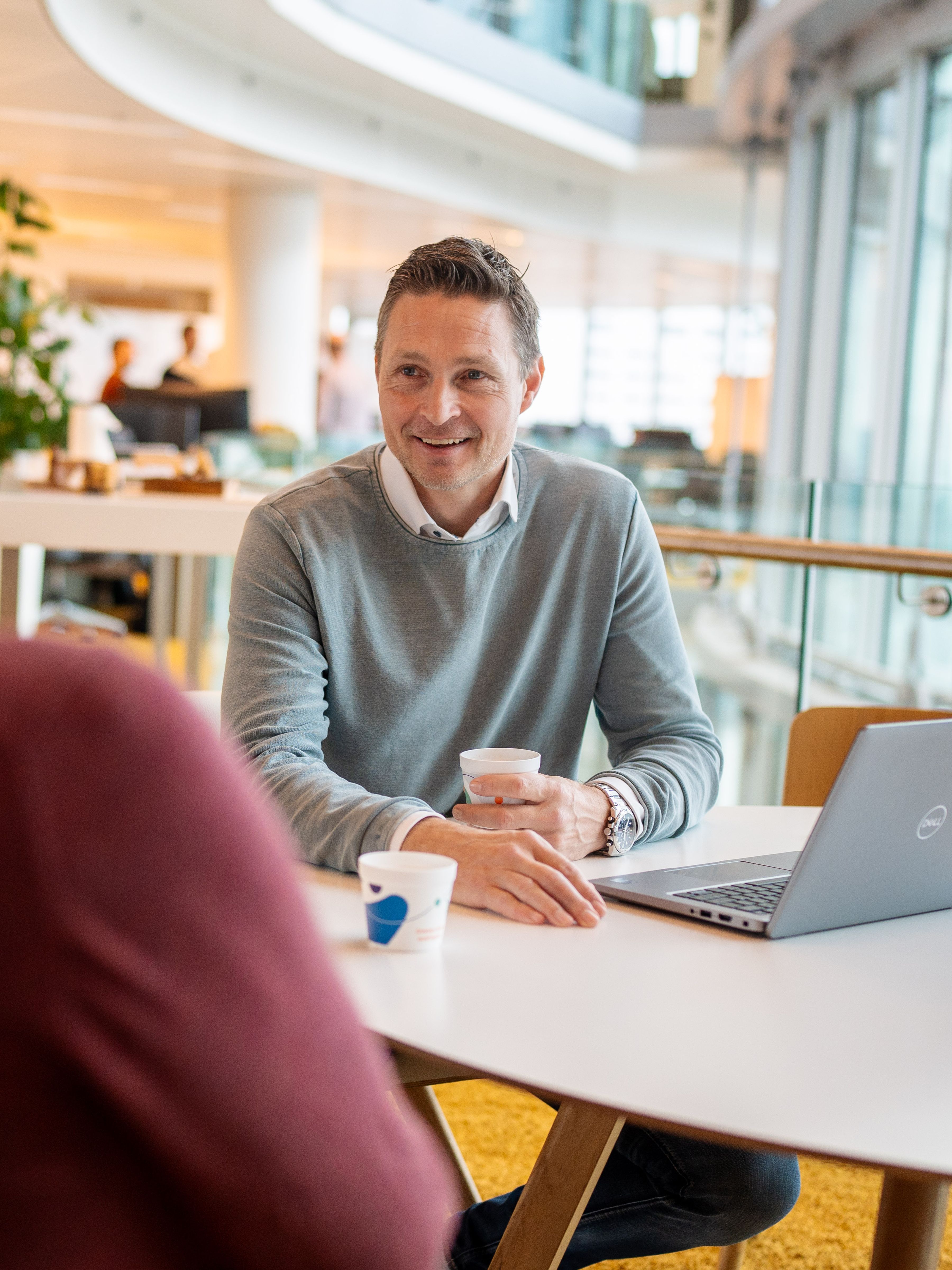 man talking with a collague next to a laptop