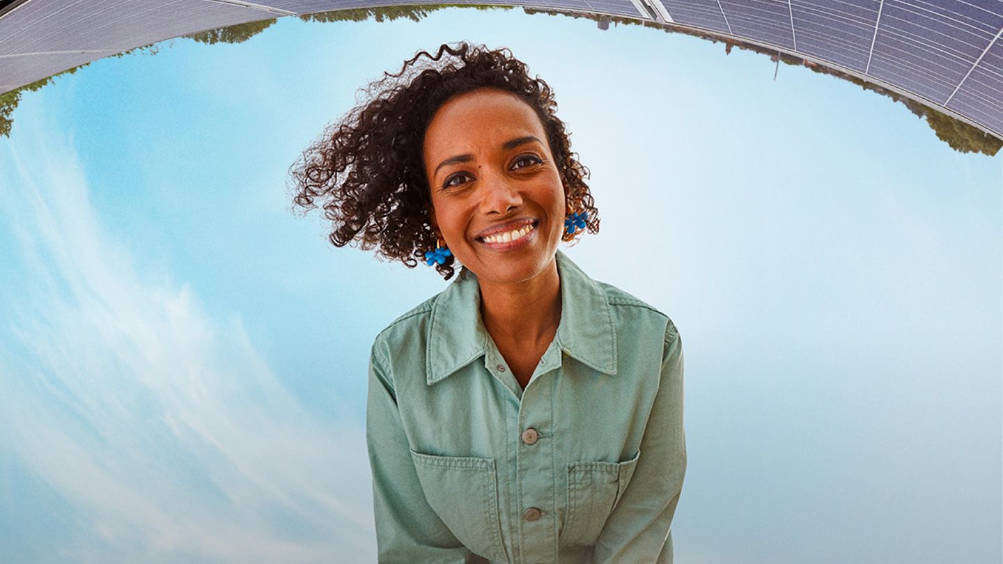 Woman smiling with solar panels in the background.