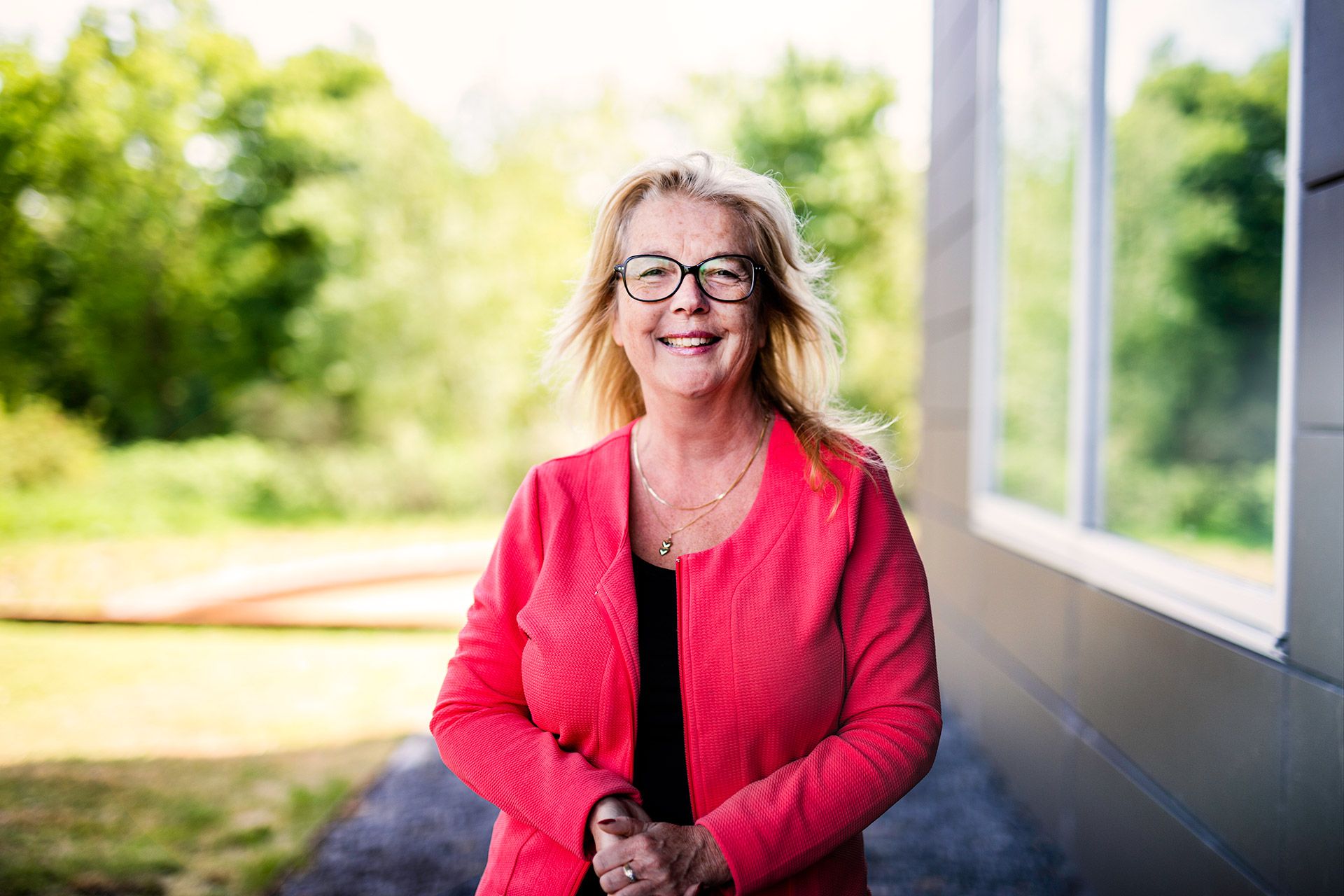 Carolien buiten naast gebouw in groene omgeving