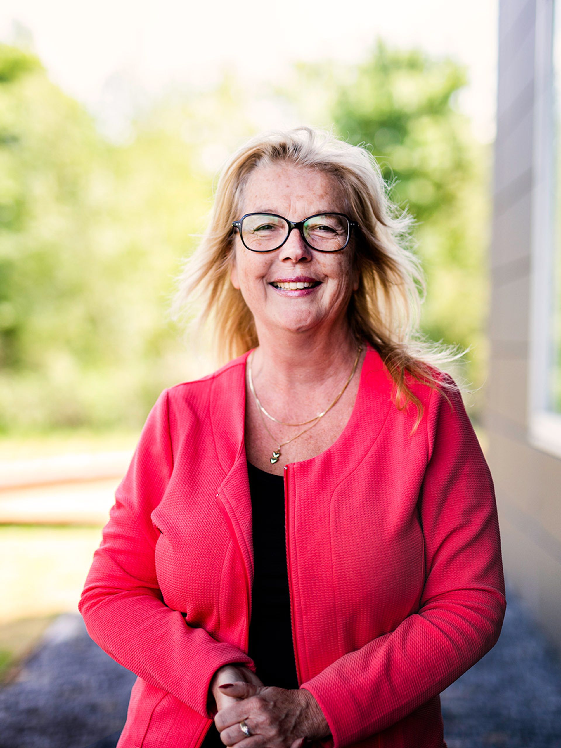Carolien buiten naast gebouw in groene omgeving