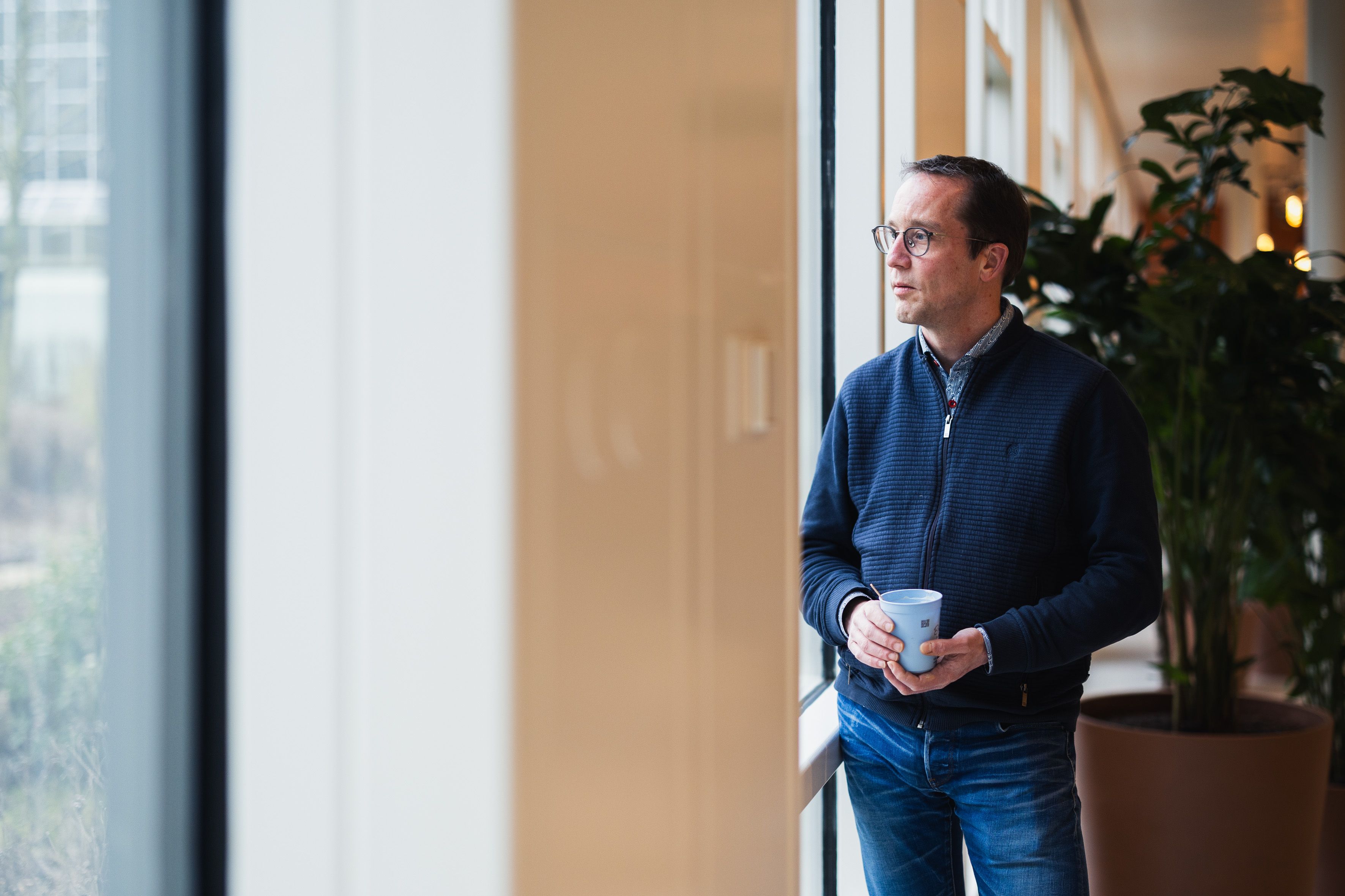 Man look outside the window with a cup of coffee in his hands