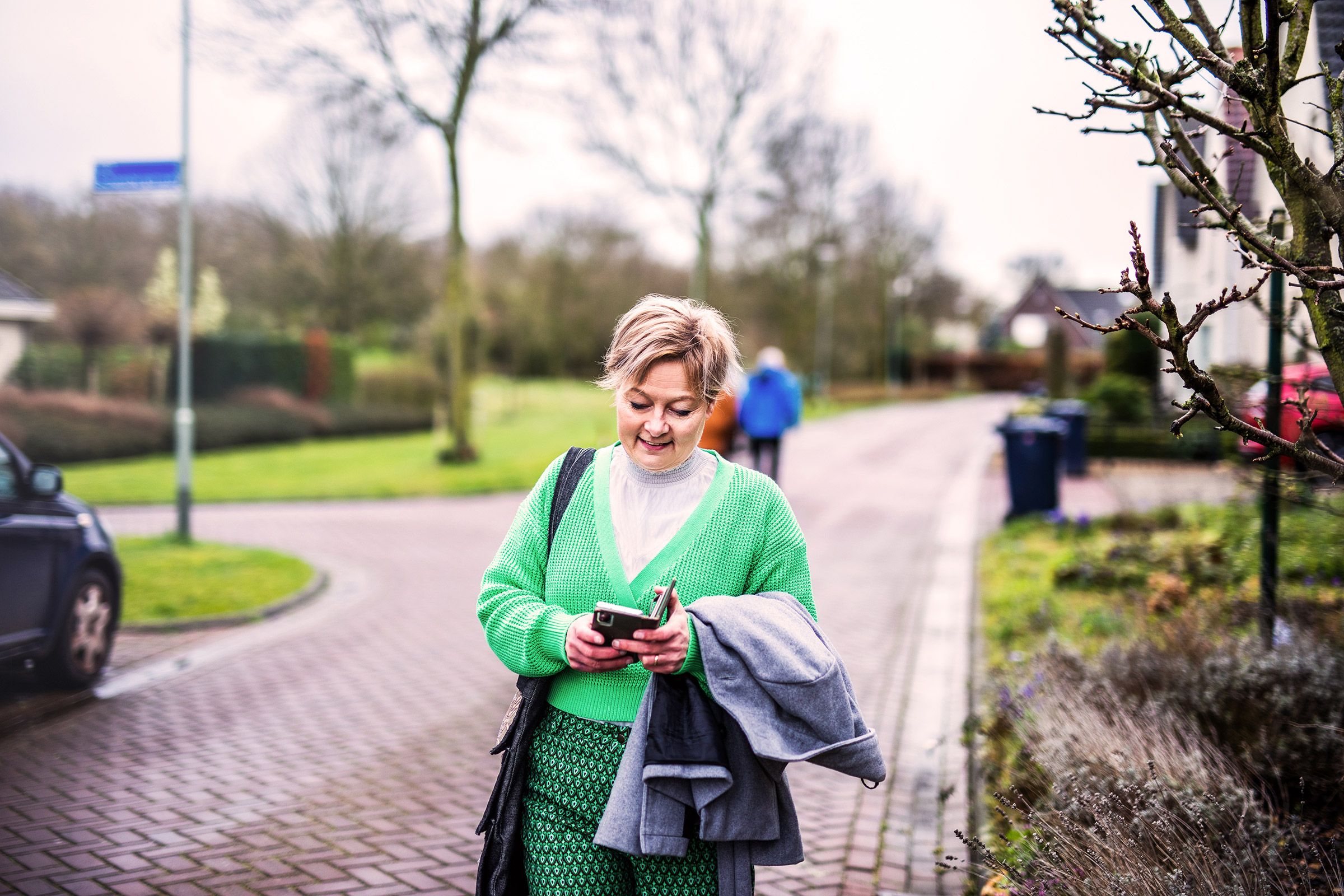 Francien walks across the street while holding her mobile phone