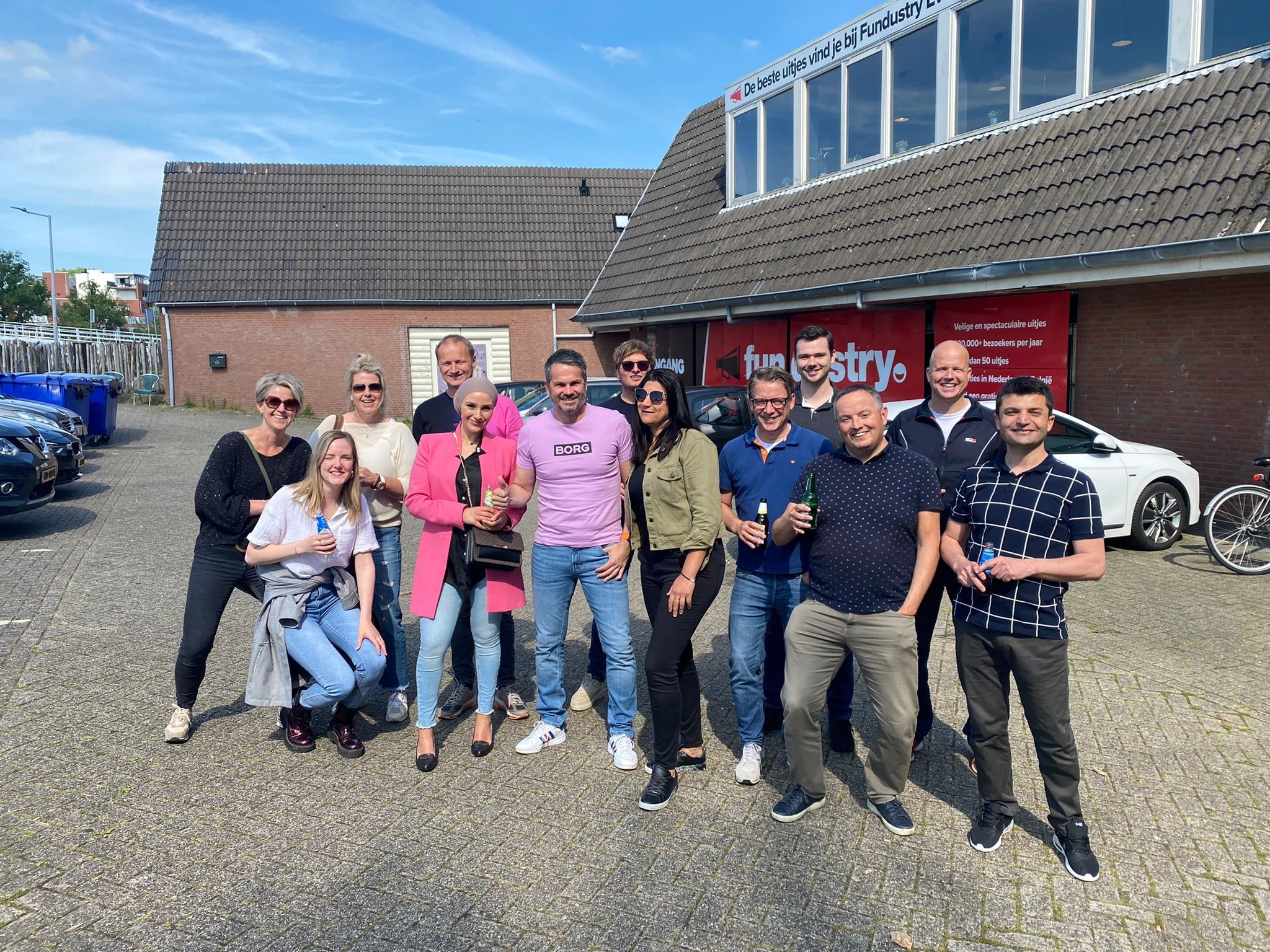 Groep mensen poseert buiten met een drankje in de hand