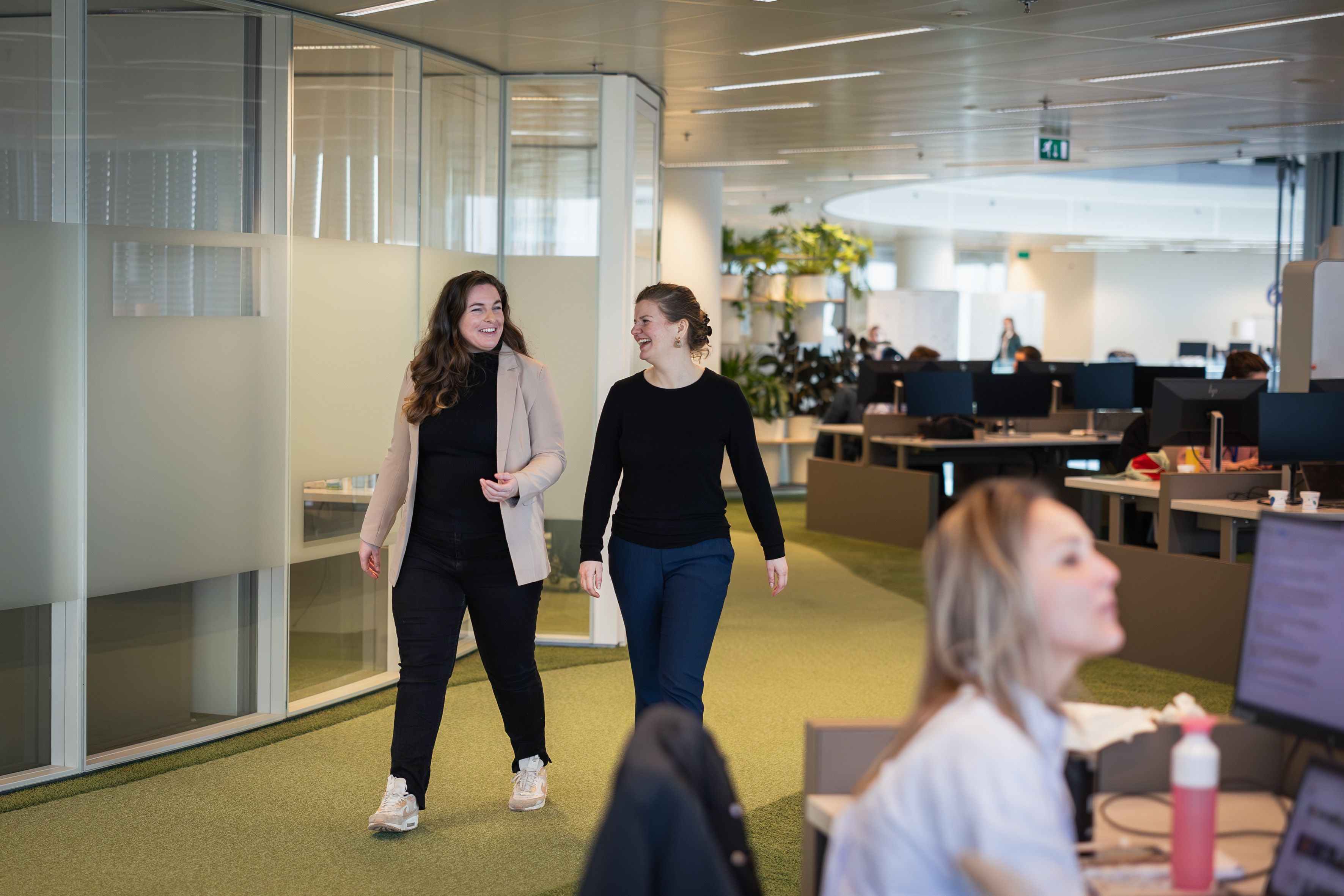 Twee vrouwen lopen al pratend over de werkvloer