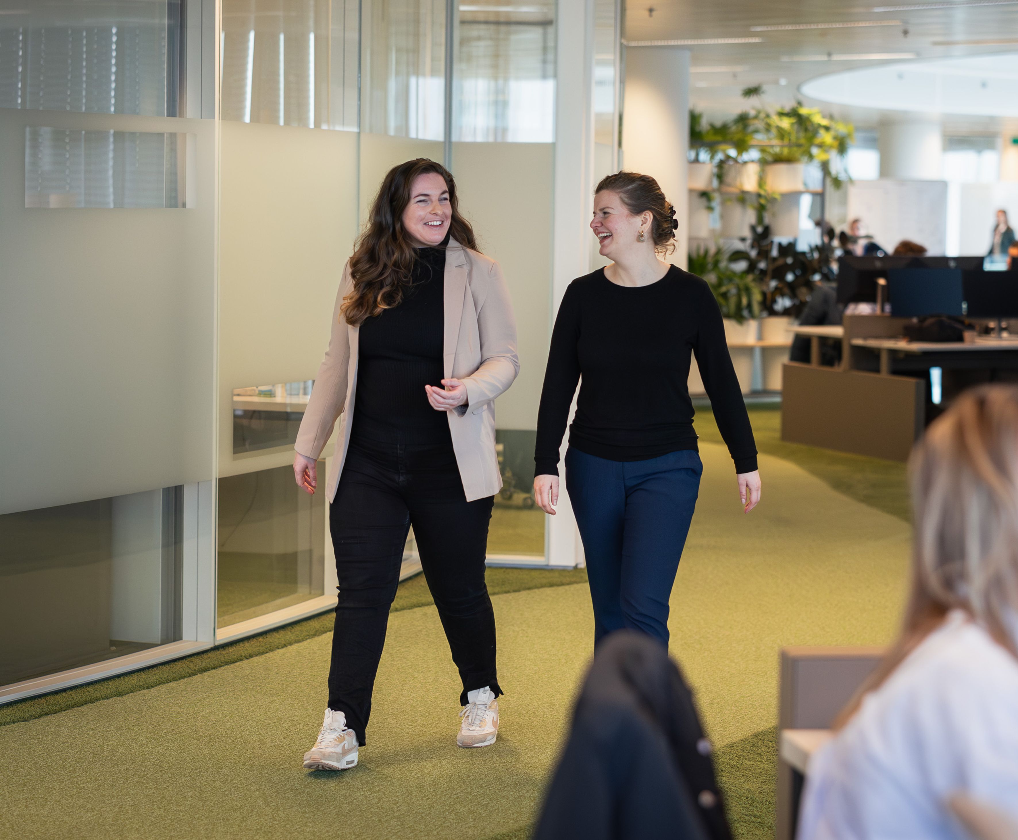 Twee vrouwen lopen al pratend over de werkvloer