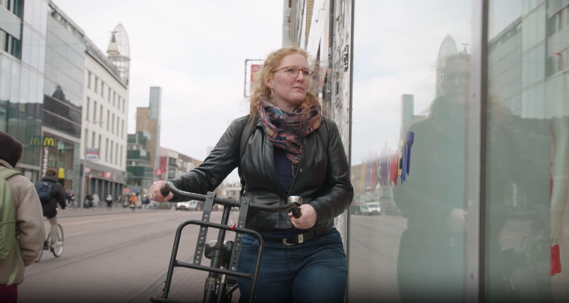 Vrouw loopt met fiets aan de hand door winkelstraat