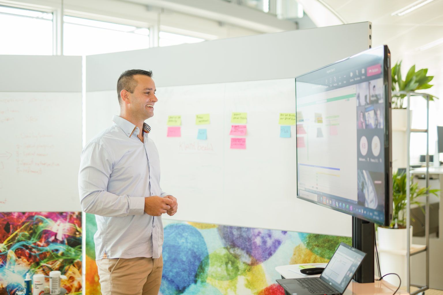 Man stands in front of monitor next to whiteboard.