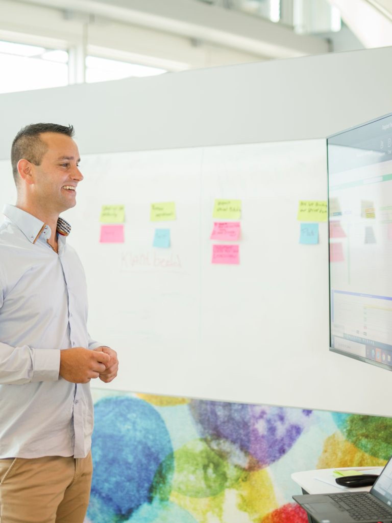 Man stands in front of monitor next to whiteboard.