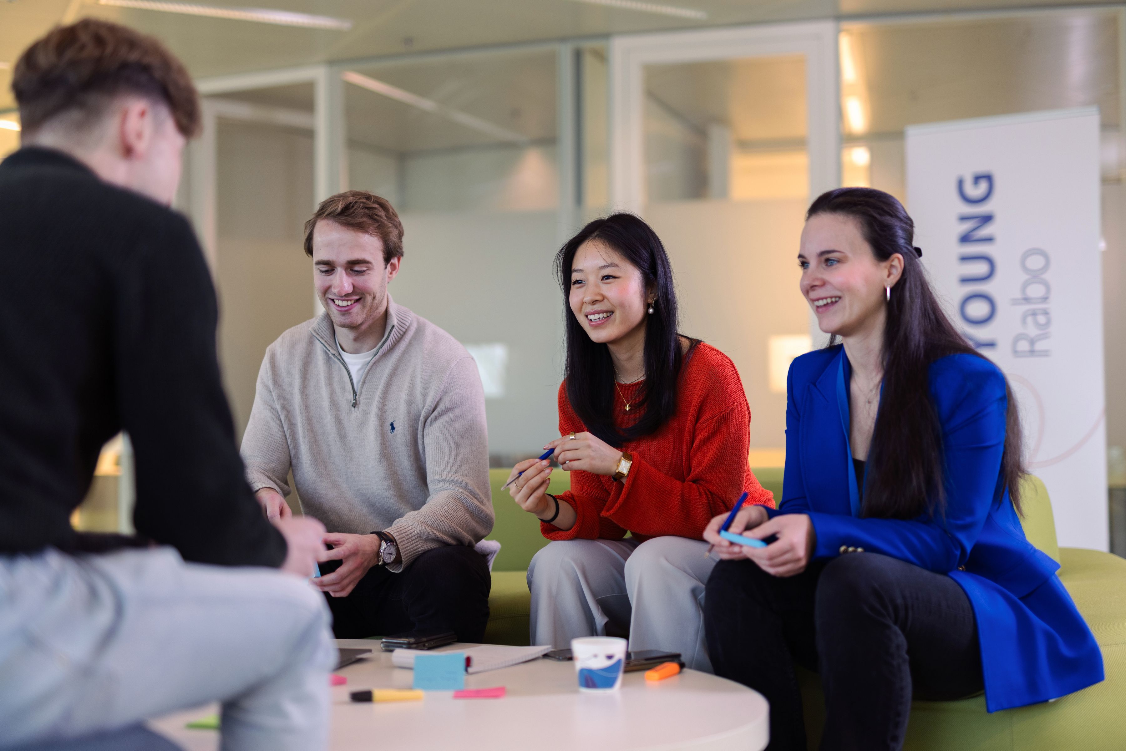 Groepje jong professionals zitten samen vrolijk op een bank