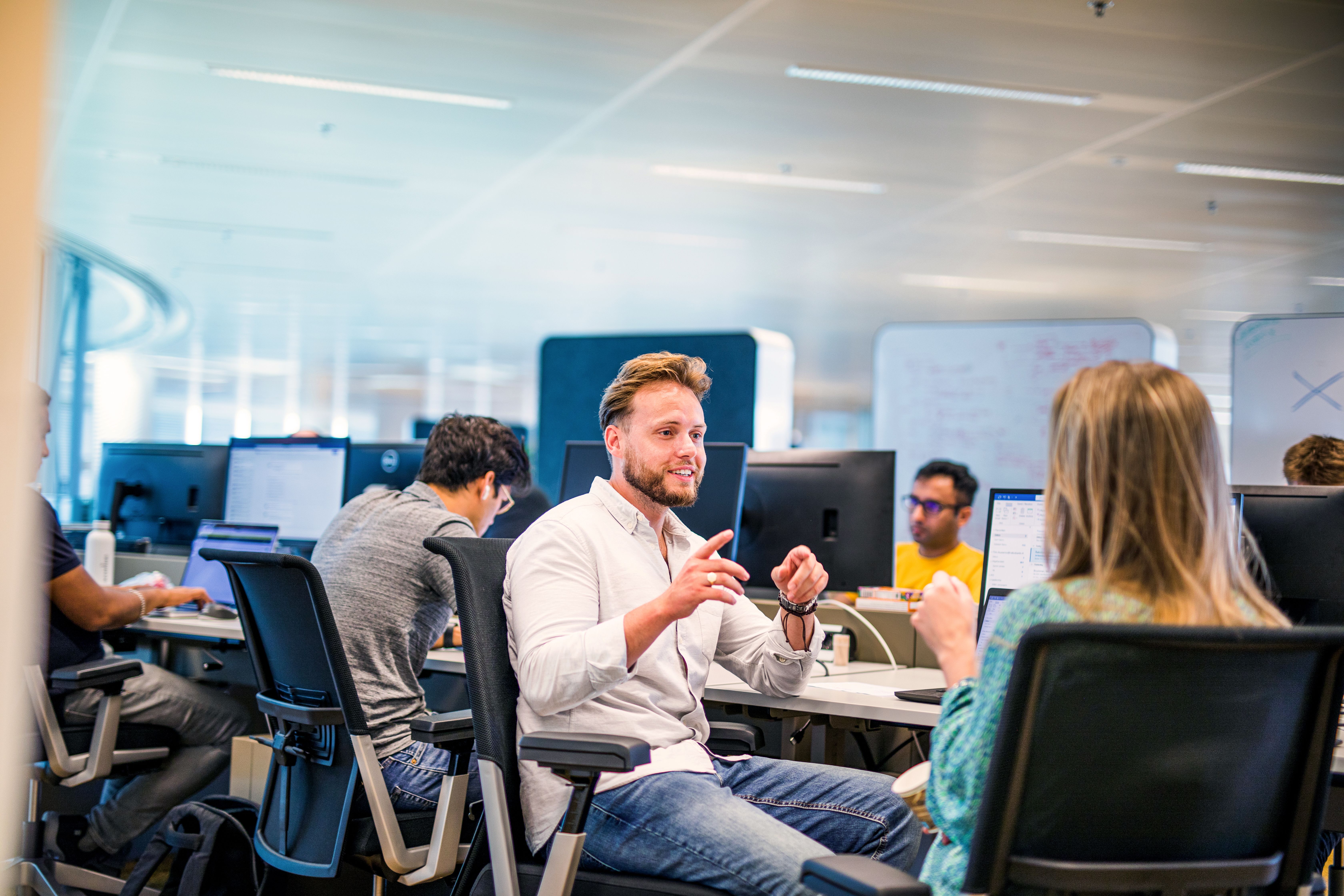 Jonge man in overleg met collega achter bureau