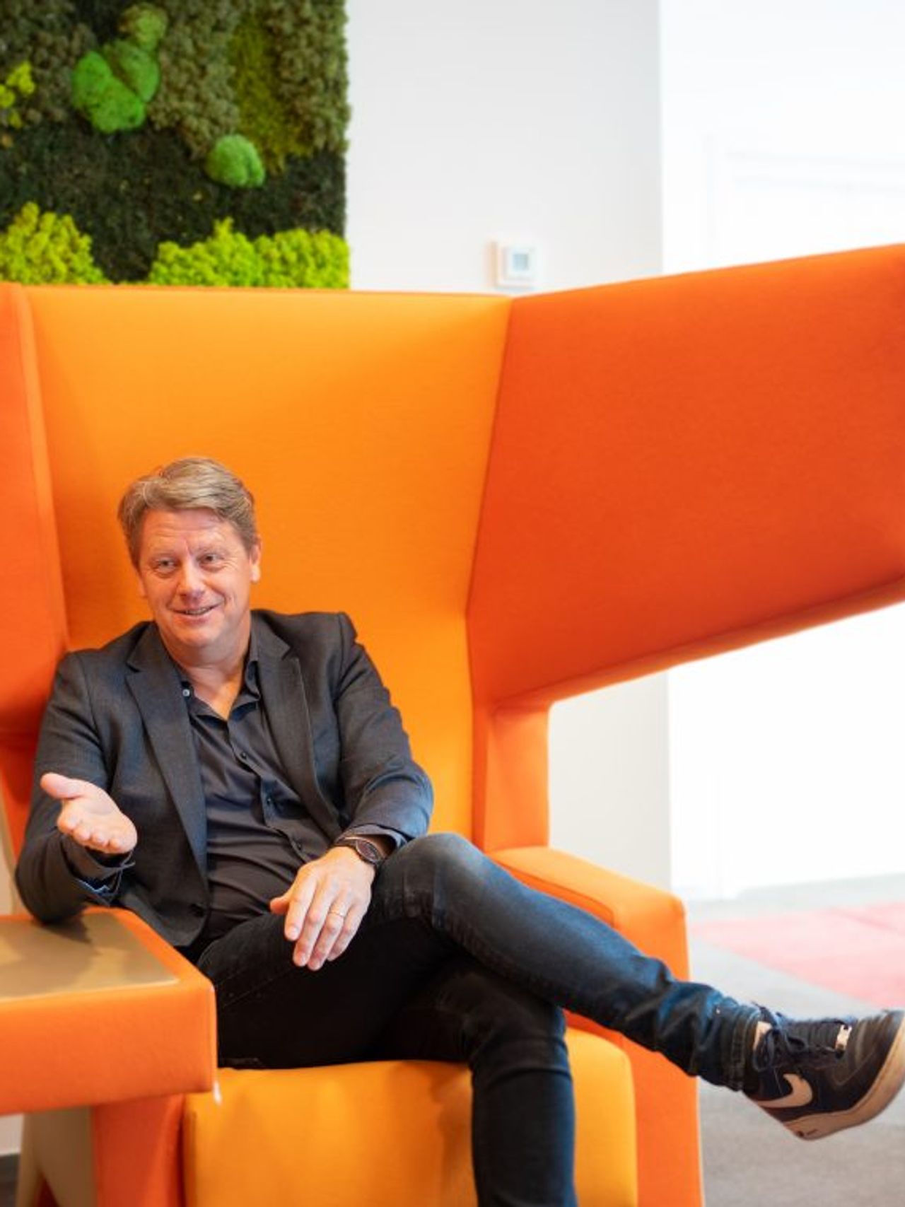Man sits in an orange chair talking to a woman
