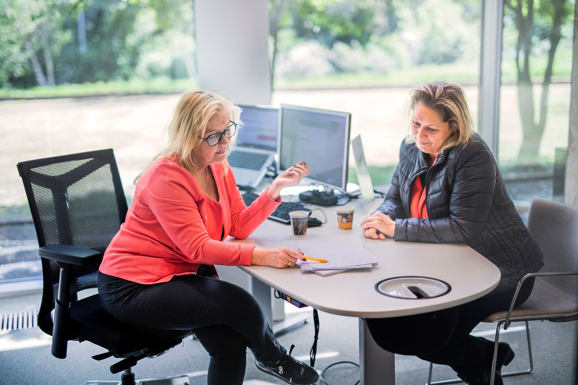 Carolien aan bureau met mevrouw, ze kijken samen naar een document