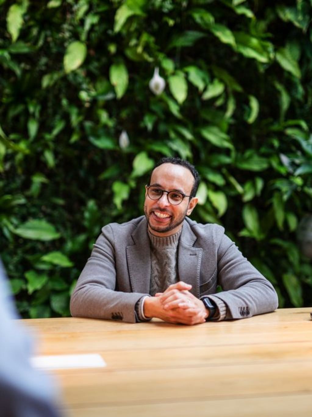 man sits smiling at table with colleagues