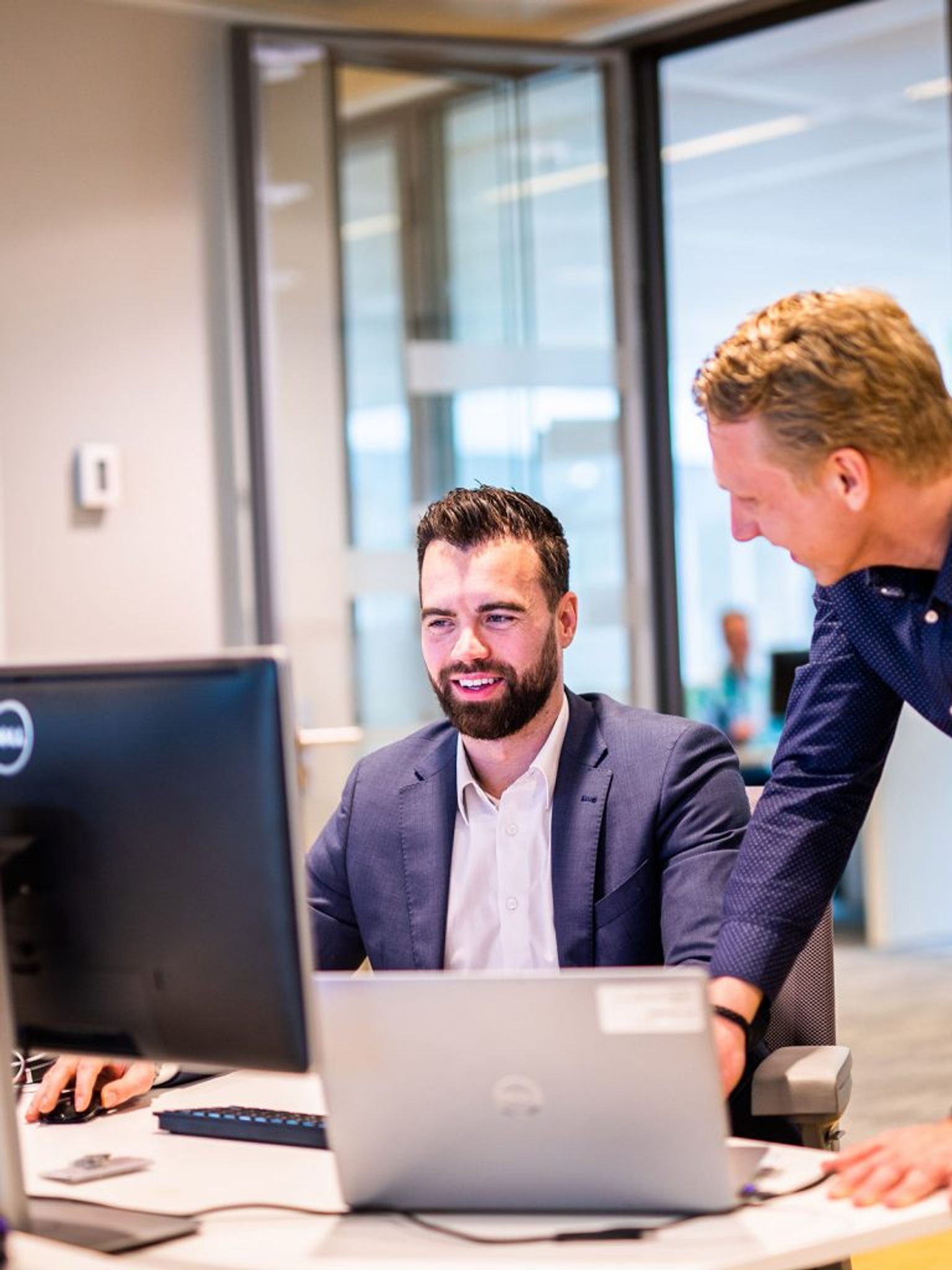 Twee mannen achter computerbeeldscherm.