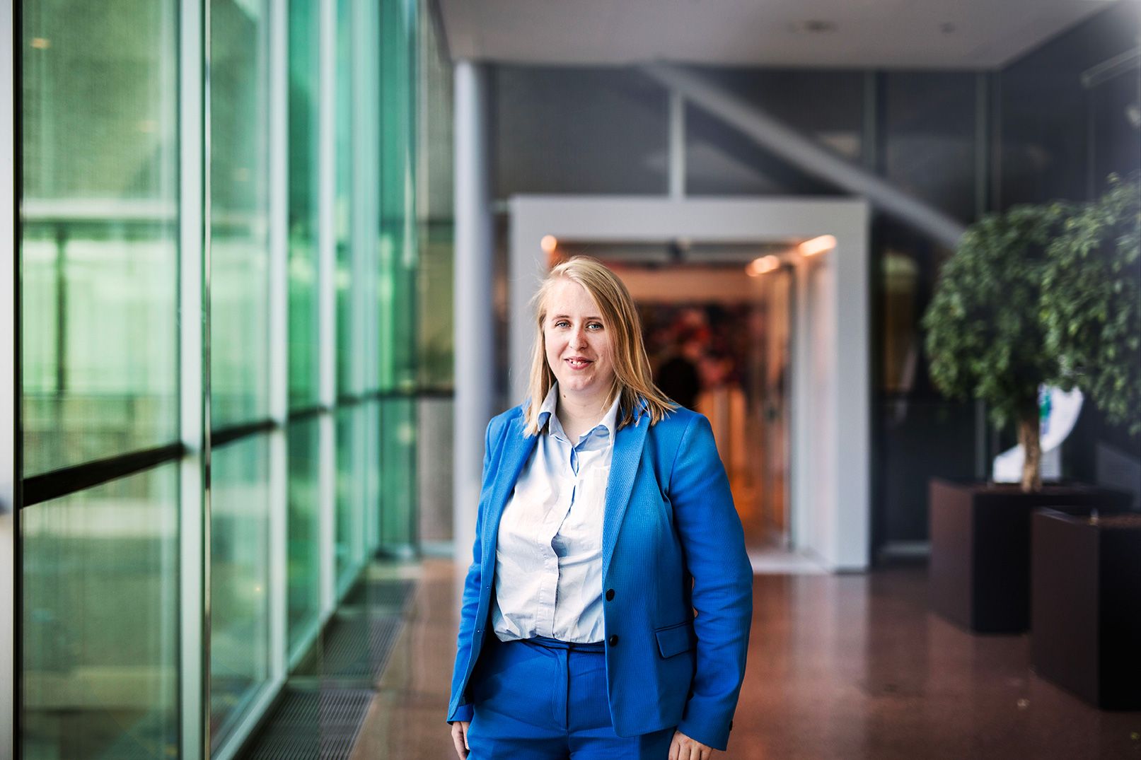 Vrouw in blauw pak (Business Controller) bij glazen wand.