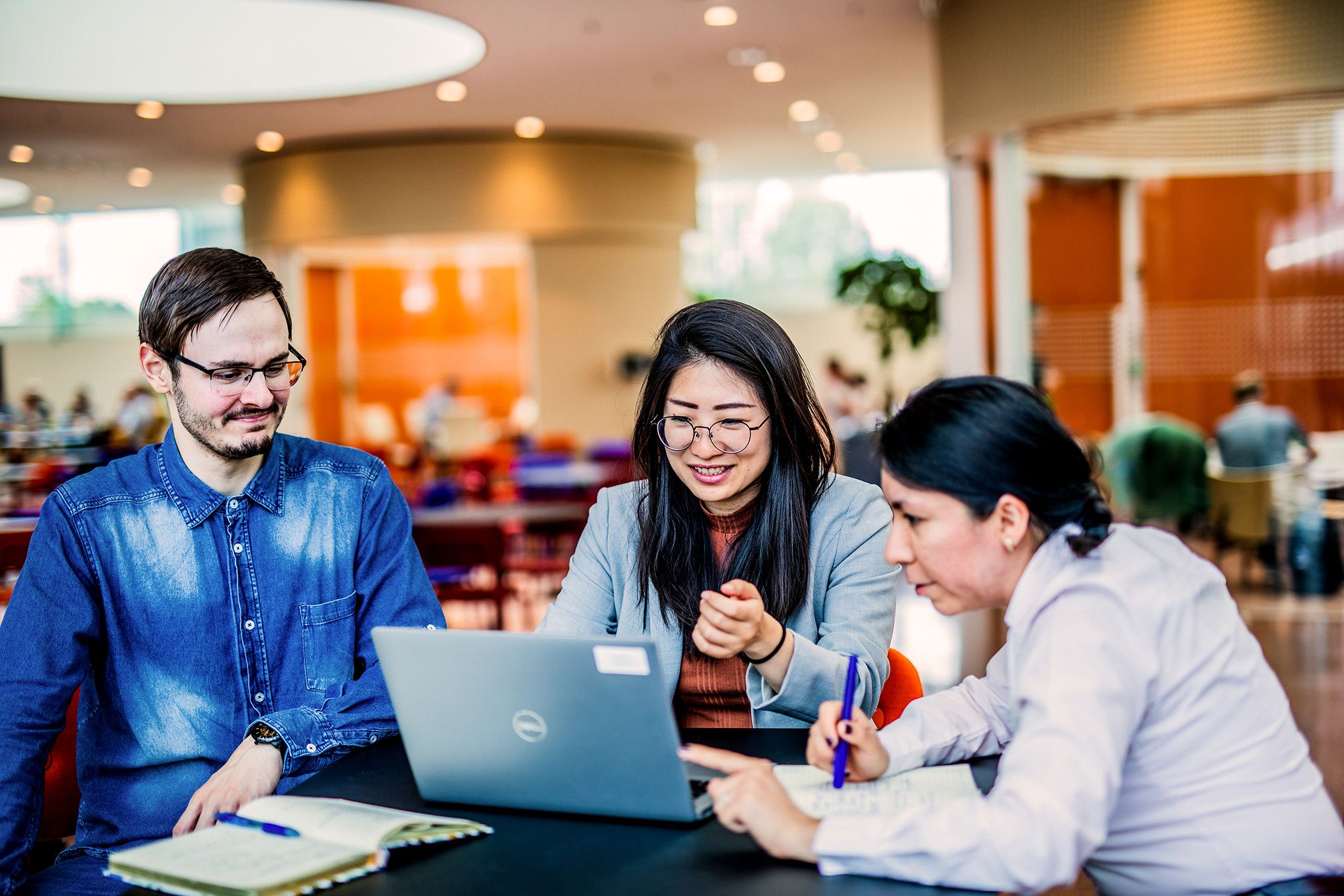 Three colleagues having a conversation behind a laptop