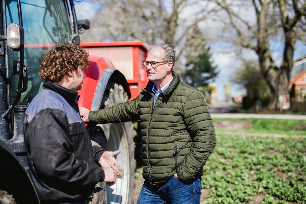 Man staat bij tractor op het land van een boer