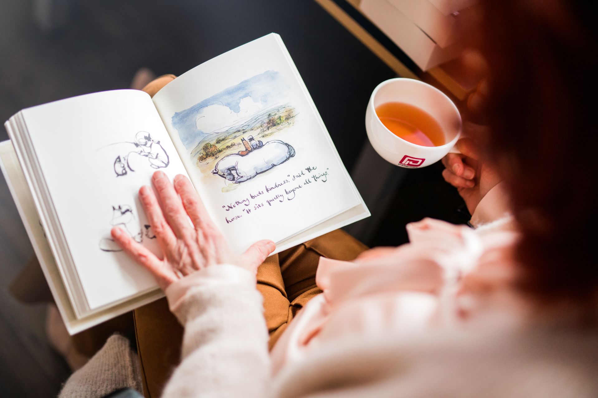 Vrouw leest boek met kop thee.