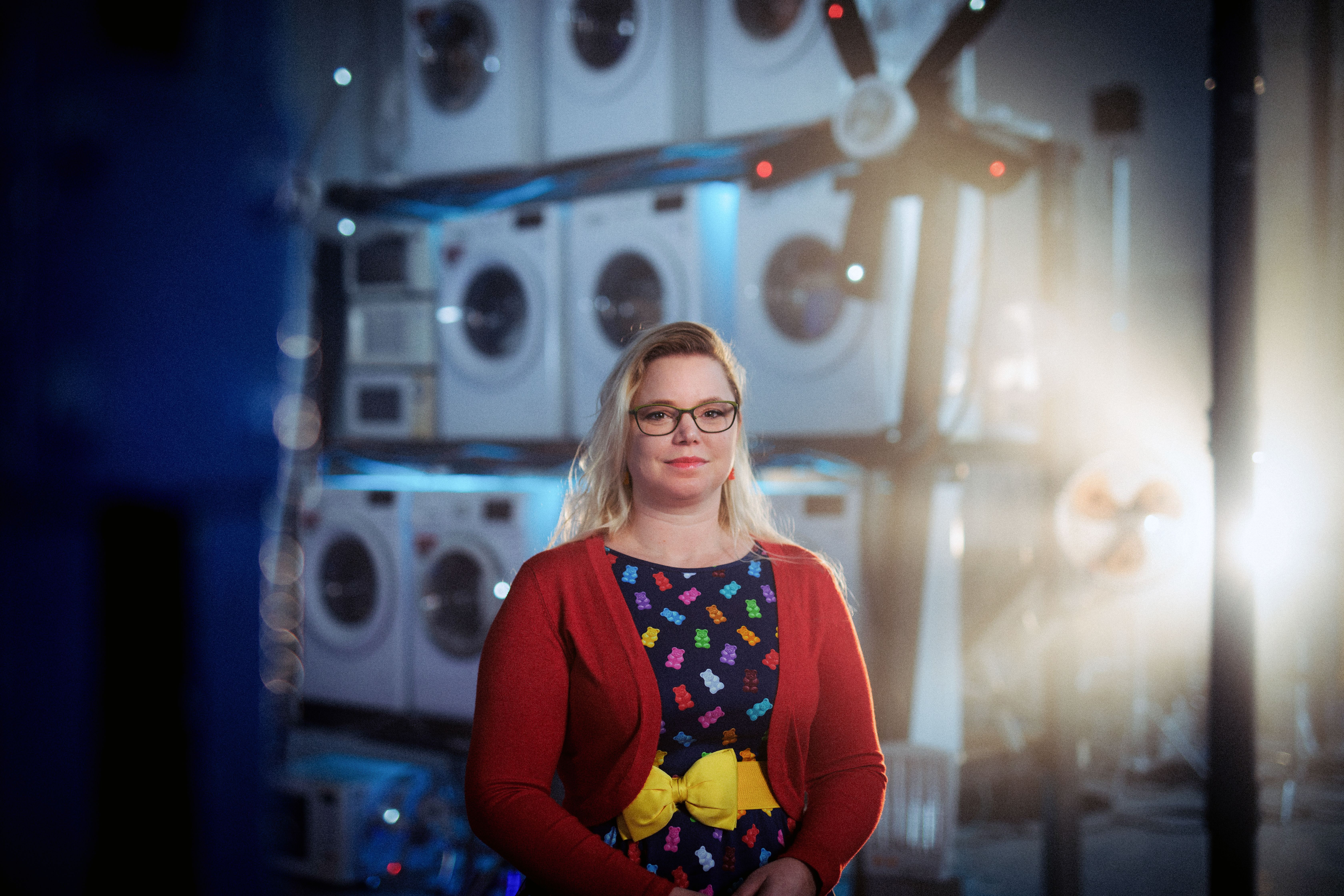 Woman standing in front of washing machines stacked up.